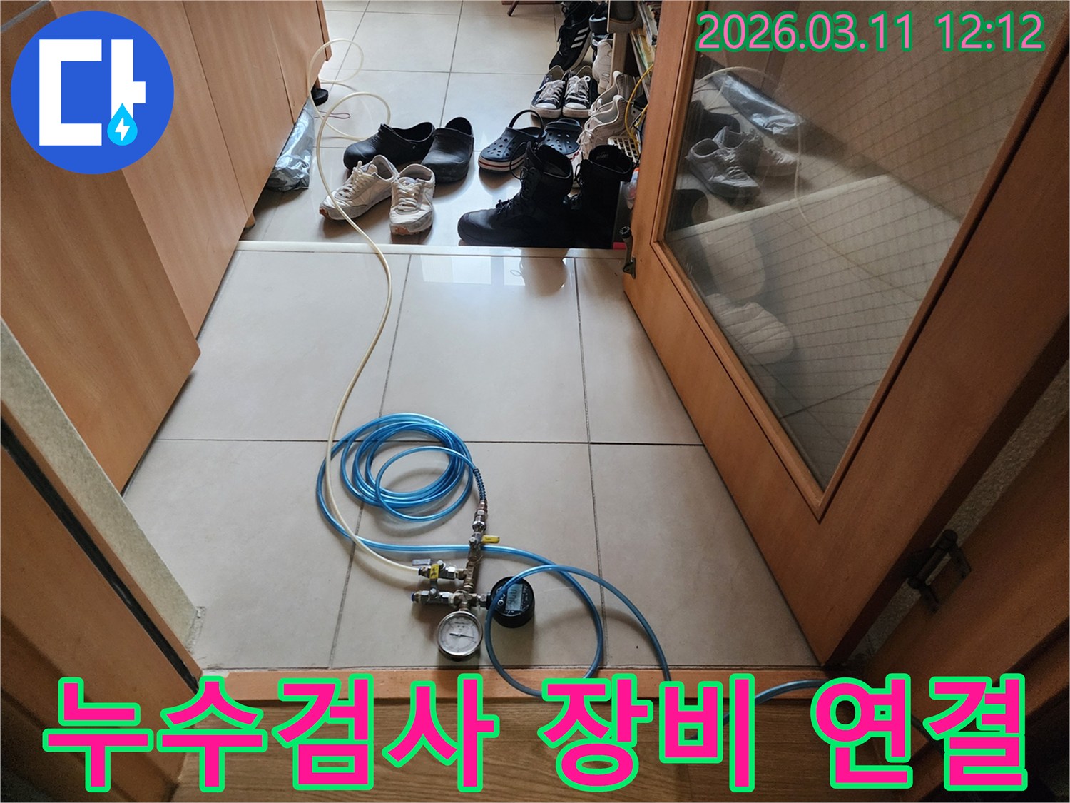 누수 탐지 작업을 위해 압력 게이지와 호스를 바닥에 연결하여 준비하는 모습