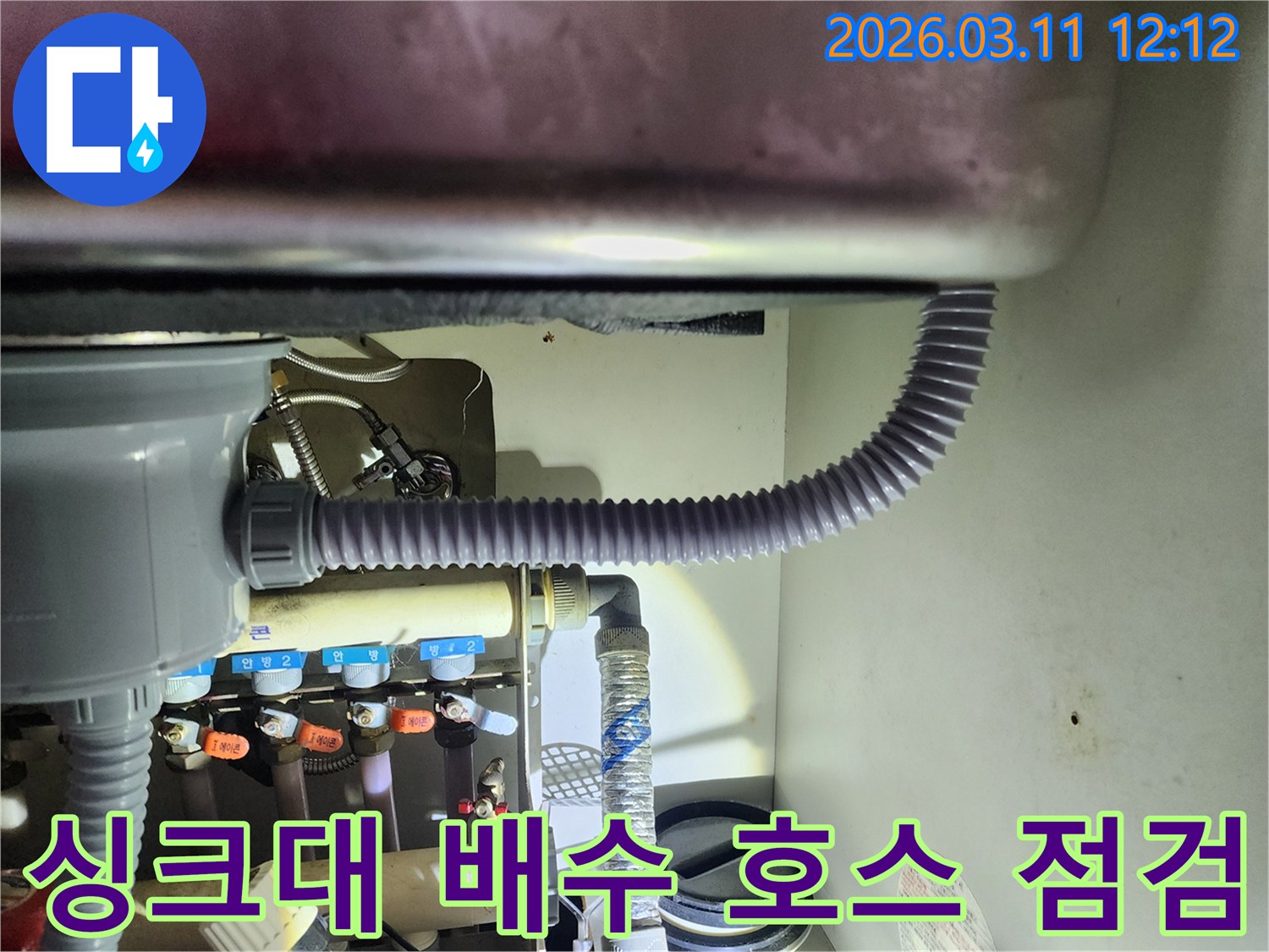 싱크대 아래쪽에서-유연한 배수 호스의-손상 여부와-연결 상태를-확인하는 장면입니다