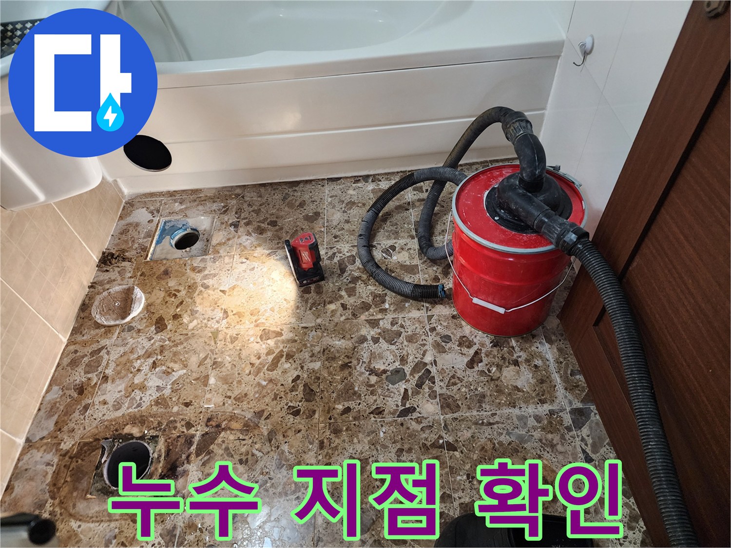 공사가 진행 중인 욕실 바닥의 배수구와 흡입 장비 연결 호스