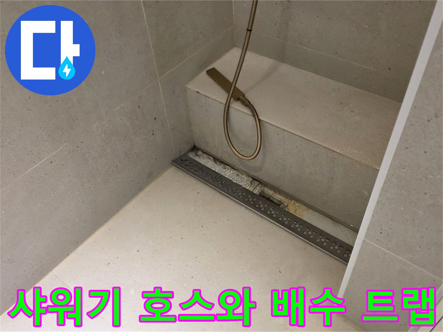 샤워기 줄이 늘어져 있는 화장실 바닥과 배수구 모습