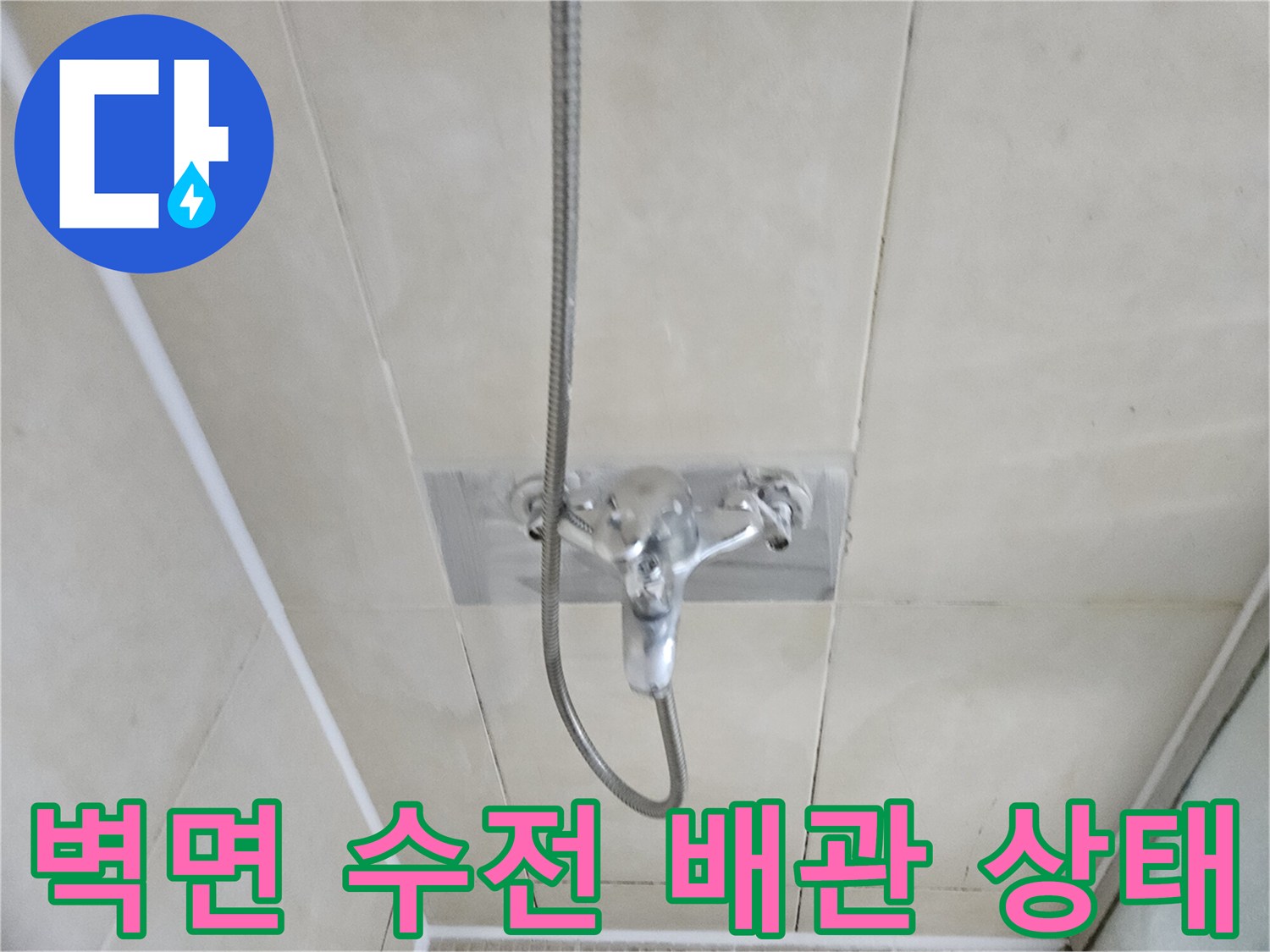 샤워기 수전과 연결된 은색 배관 호스 및 타일 벽면