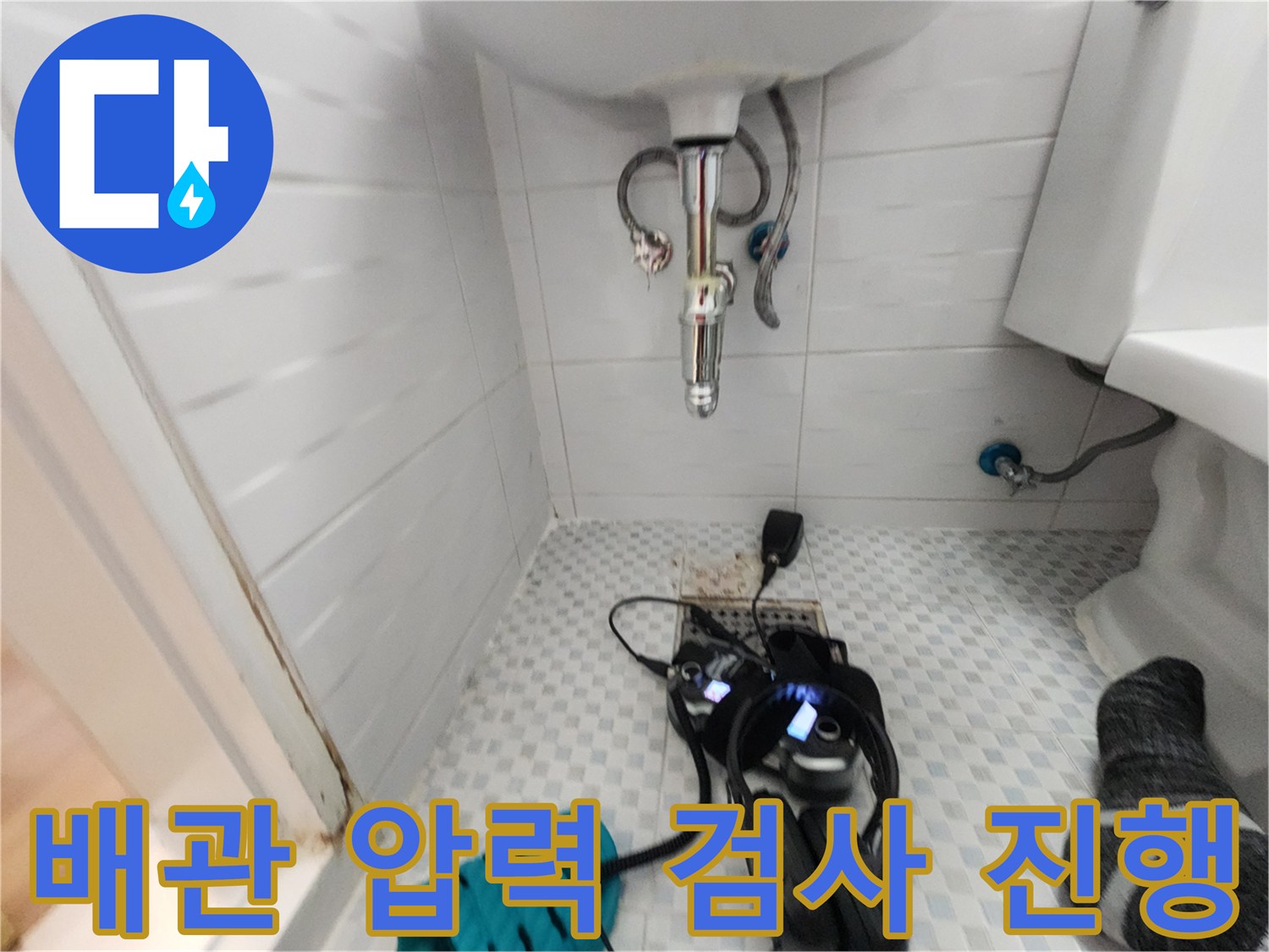 세면대 밑 바닥에 놓인-공압 측정 장치와-수도 점검용 헤드셋