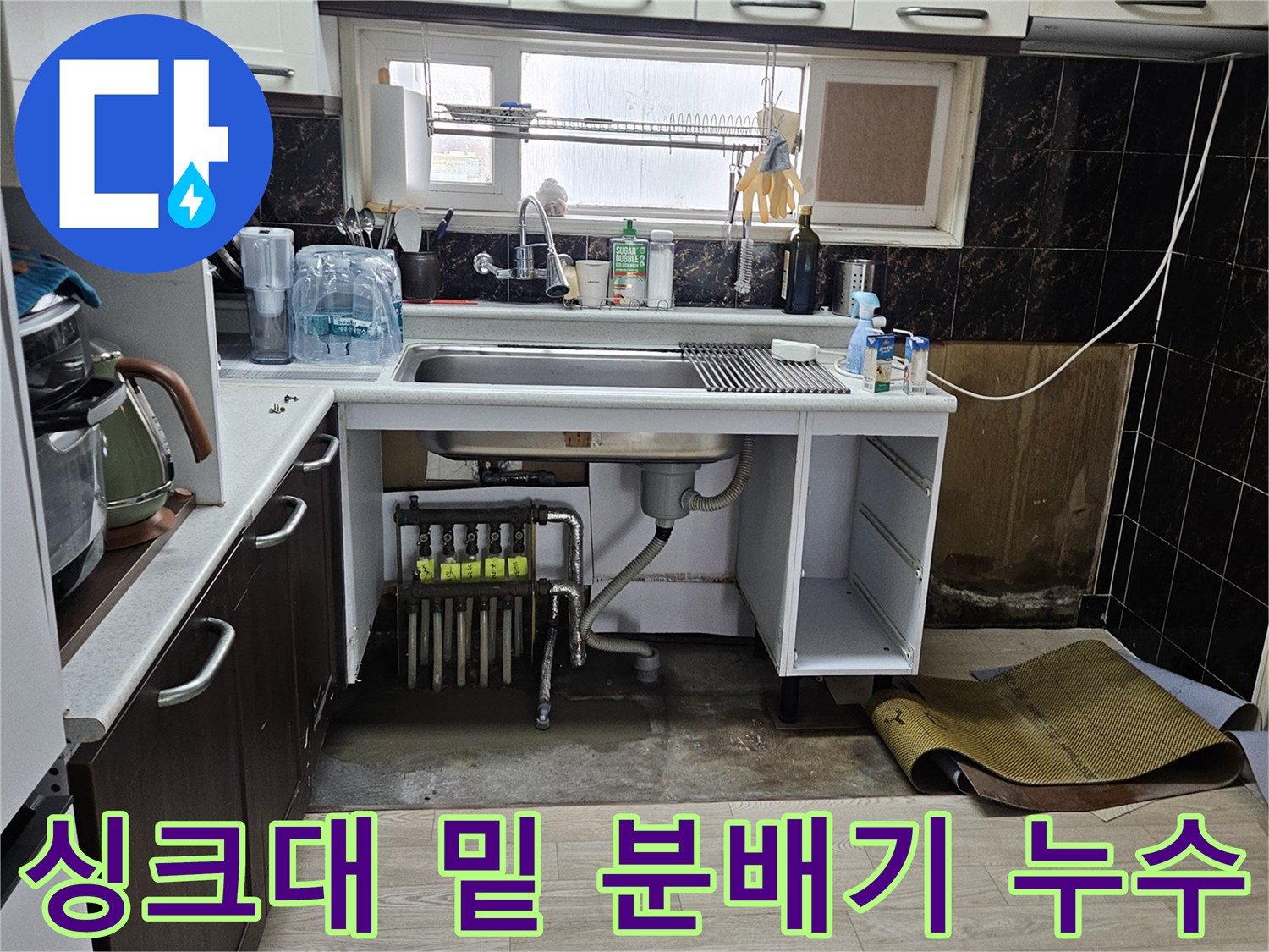싱크대 하부장 안쪽의 물기에 젖은 바닥과 배관 부속들