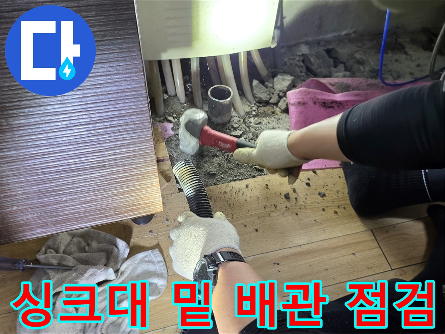 싱크대 아래 좁은 공간-배관 주변을 확인하는 작업자