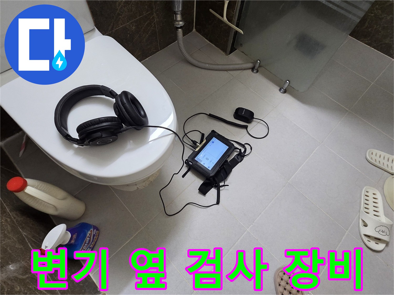 화장실 바닥에 놓인 압력계와 헤드셋-배관 누수 정밀 진단 중