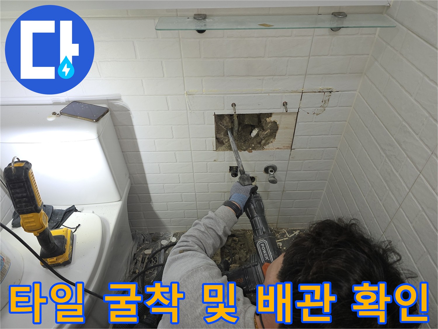 세면대 하단 타일을 제거하고 내부 배관을 노출시키는 공사 장면입니다.