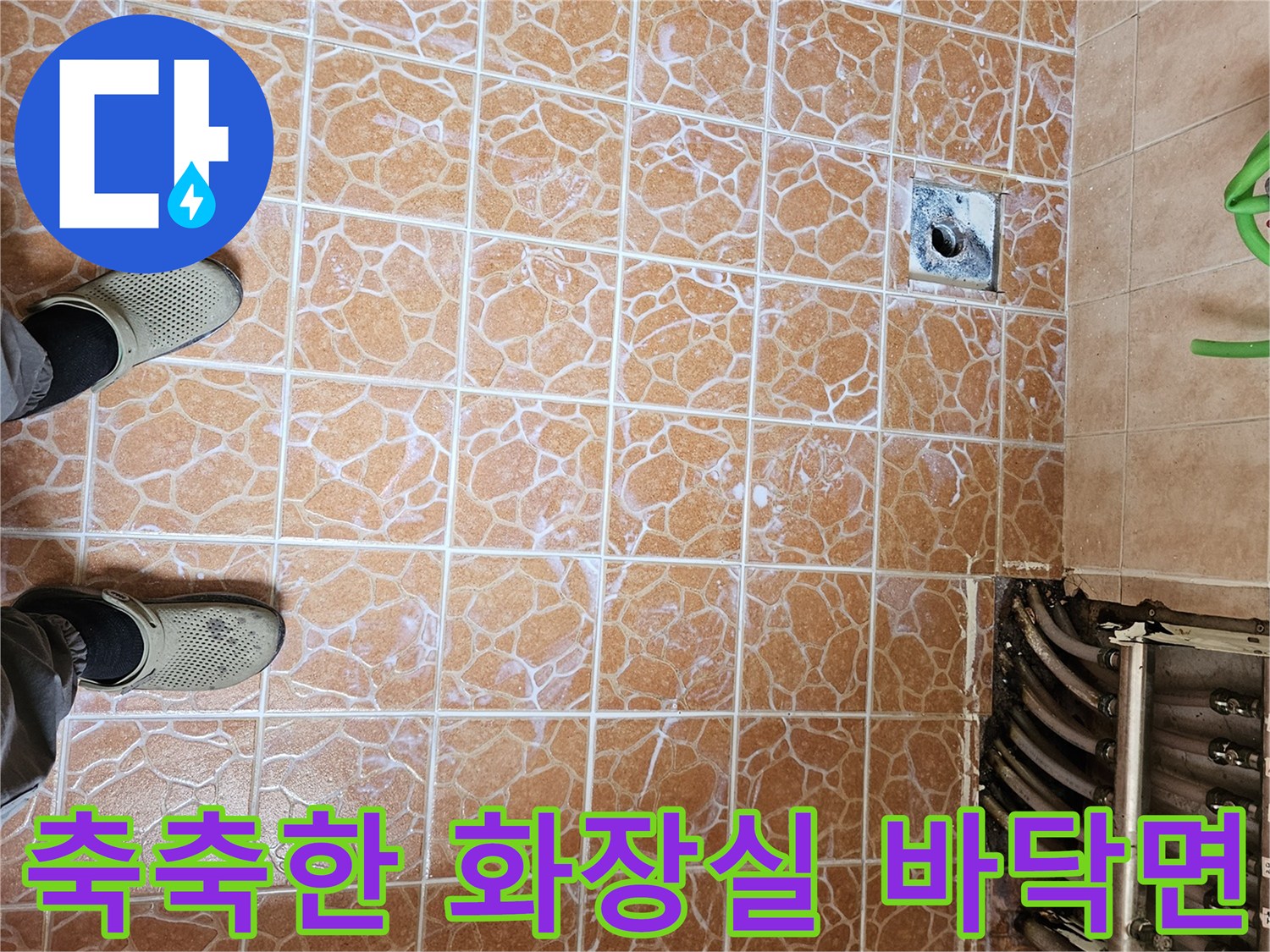 물기가 맺힌 욕실 타일과 분배기 근처 배수구를 찍은 사진입니다.