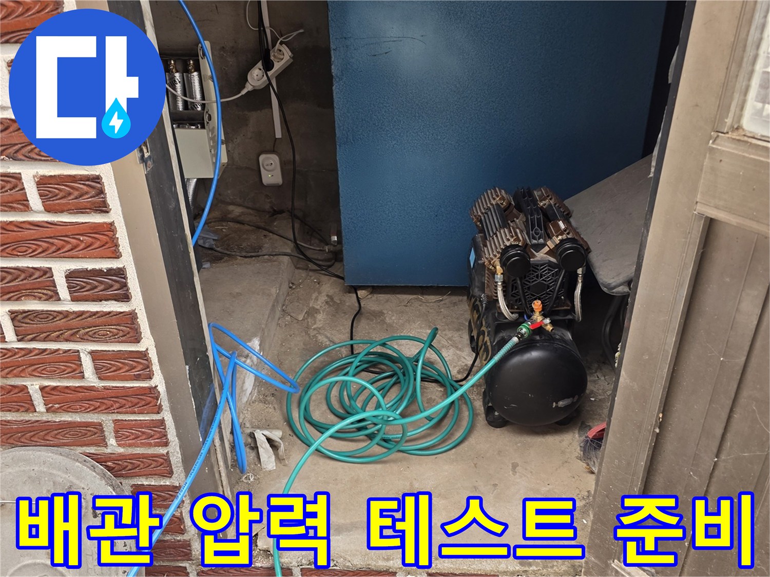현장 바닥에 놓인 검은색 에어 탱크와 파란색 연결 호스