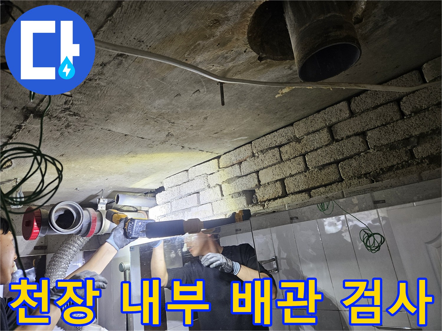 손전등 빛을 이용해 천장 배관의 누수 흔적을 찾는 작업