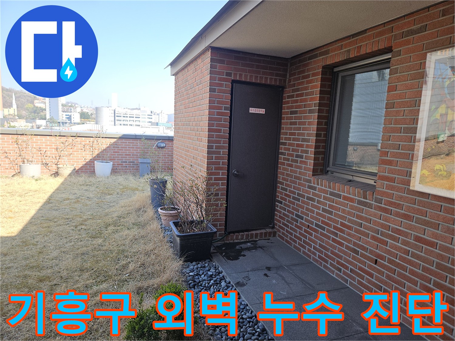 붉은 벽돌로 된 건물 외벽과 배수 시설의 접합부를 촬영한 사진
