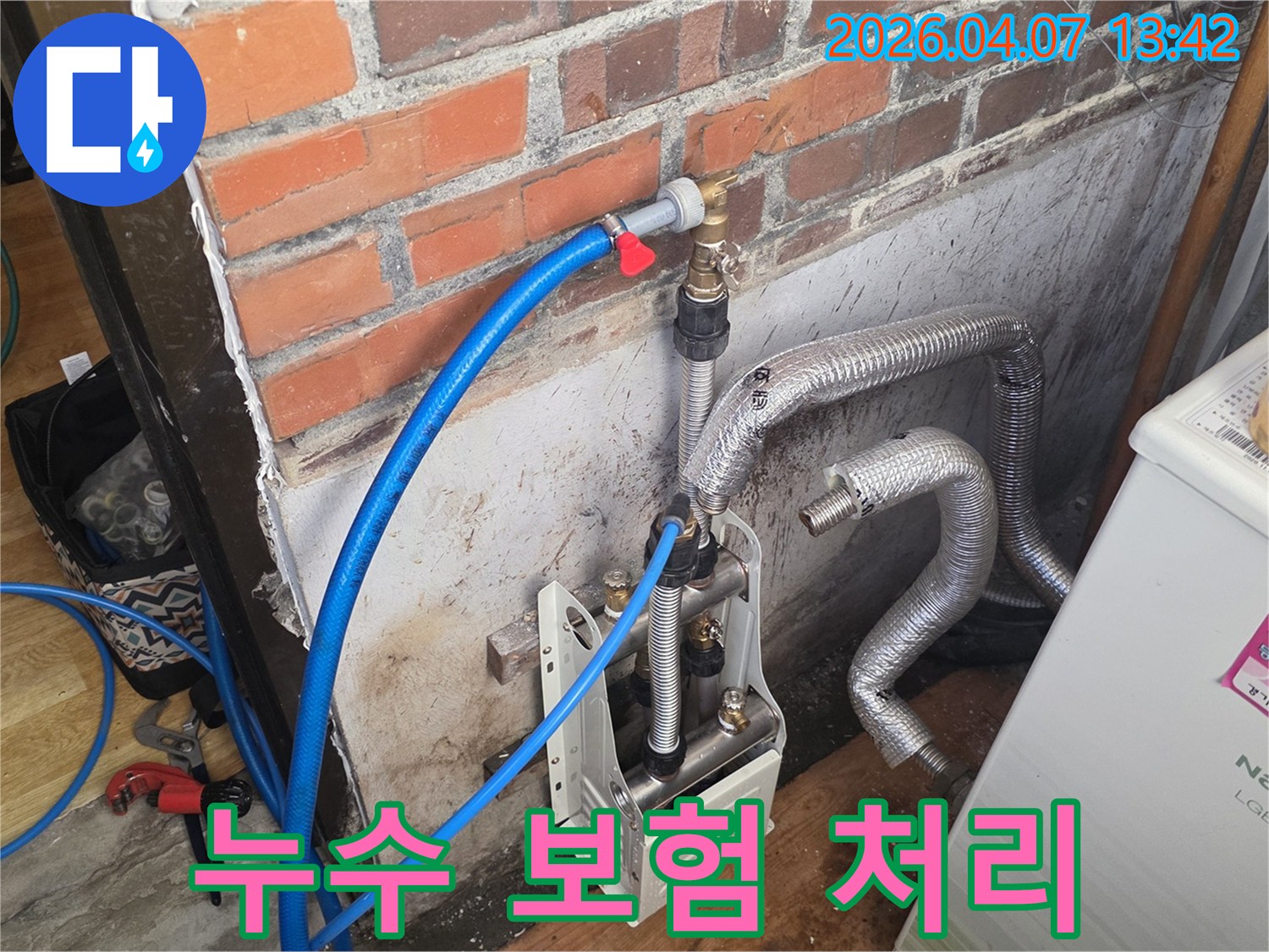 벽돌 벽 옆에-누수 탐지 장비와-배관들이 놓여 있으며-누수 보험 처리를 위한-현장 진단이 진행 중입니다.