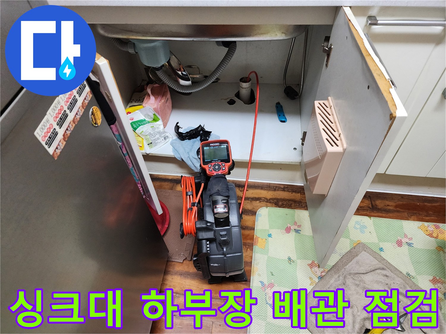 주방 싱크대 하부장 내부의 배수 호스와 석션 장비 모습