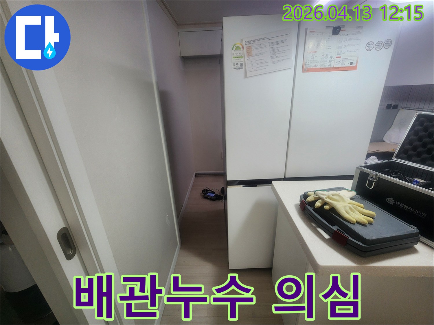 누수 탐지 전문가가-냉장고 옆 좁은 공간에서-배관 누수 여부를 확인하기 위해-준비하는 모습