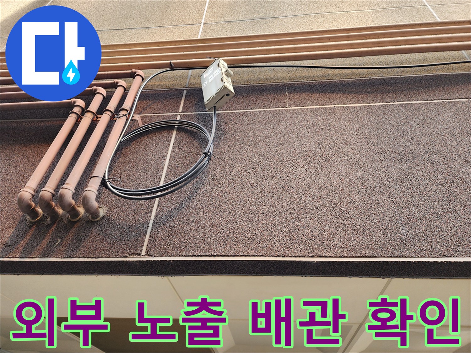 외벽에 고정된 갈색 관과 검은 케이블 사진