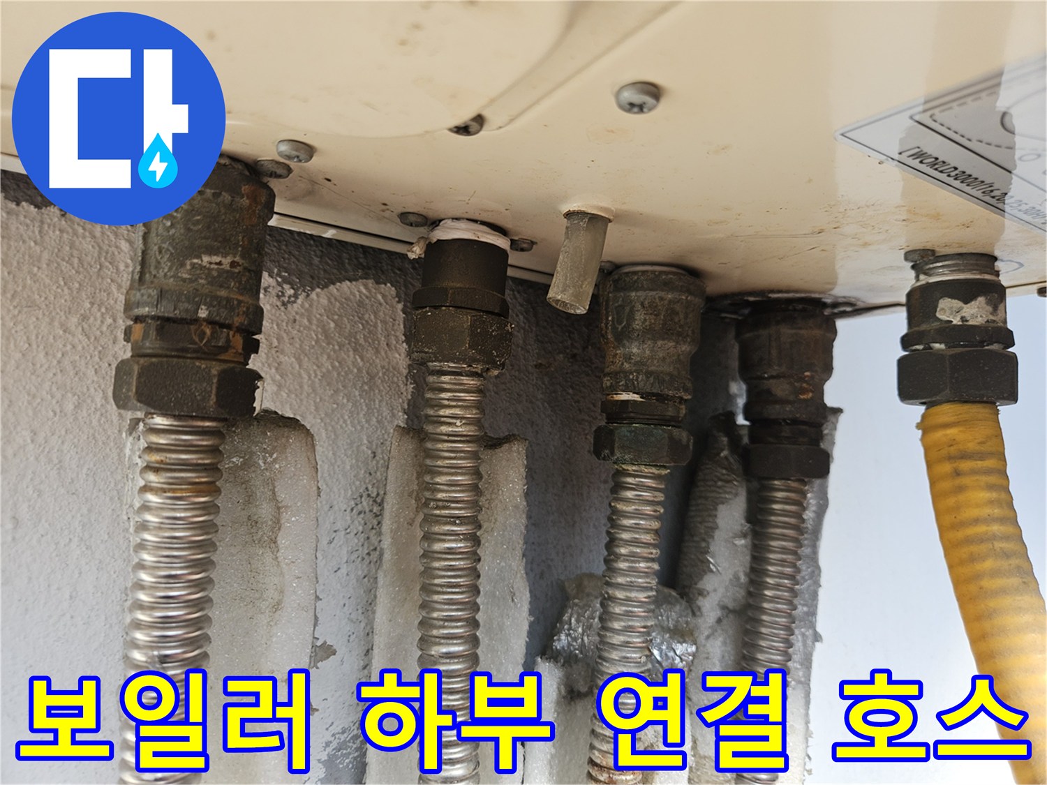 보일러 아래로 뻗어 나온 은색 주름관과 노란 호스