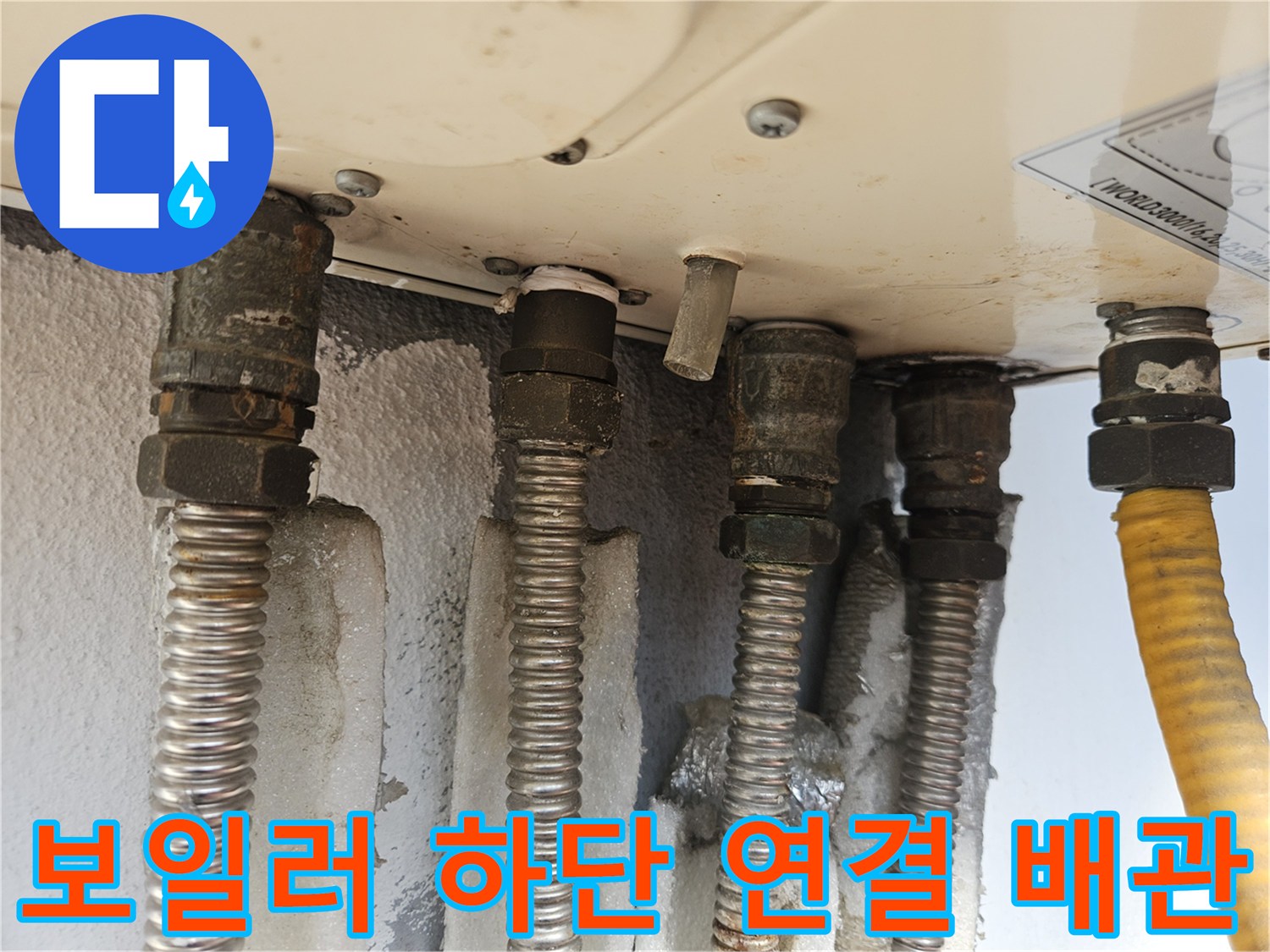 보일러 아래쪽으로 뻗어 있는 은색 주름관과 노란 호스