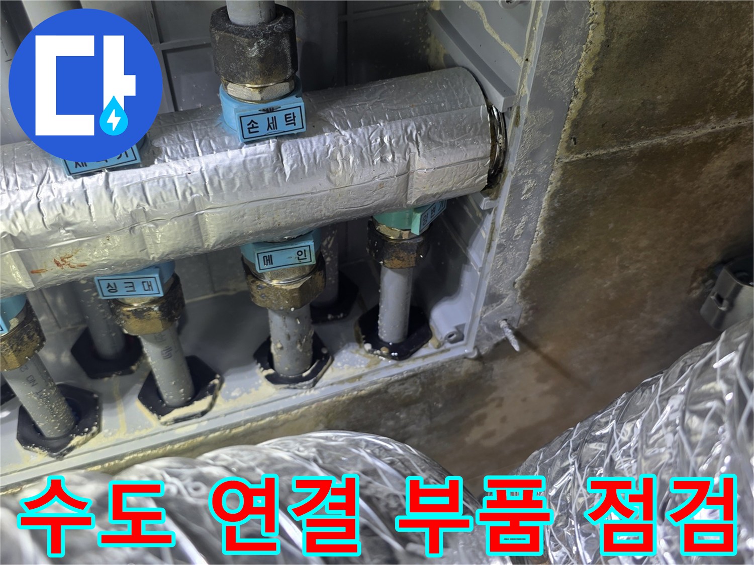 벽면에서 나온 은색 보온재 배관과 파란색 라벨링된 부속