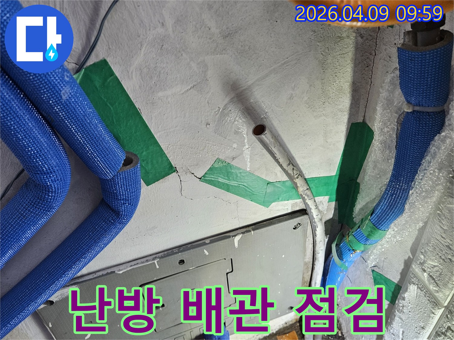 벽면의-콘크리트 균열과-파란색 보온재로 덮인-난방 배관-그리고 오렌지색 파이프가-함께 노출된-누수 점검 현장