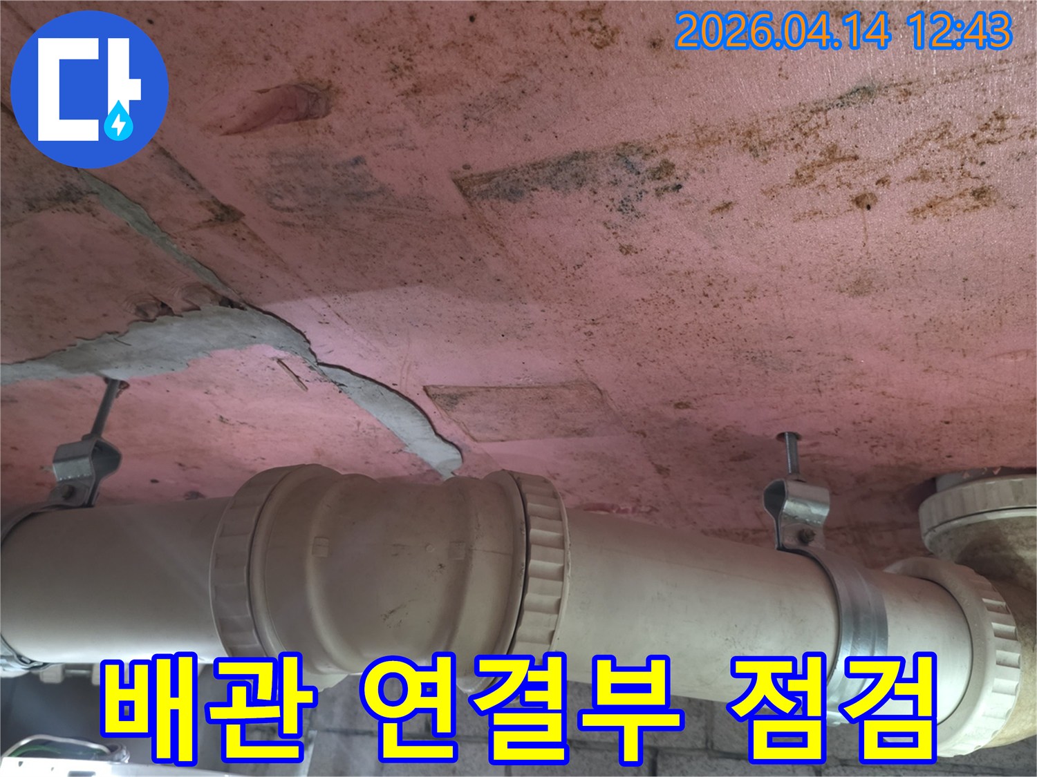 배관의 이음새 부분에서 발견된-누수 흔적과-천장 마감재의 손상을-함께 보여주는 현장 이미지입니다.