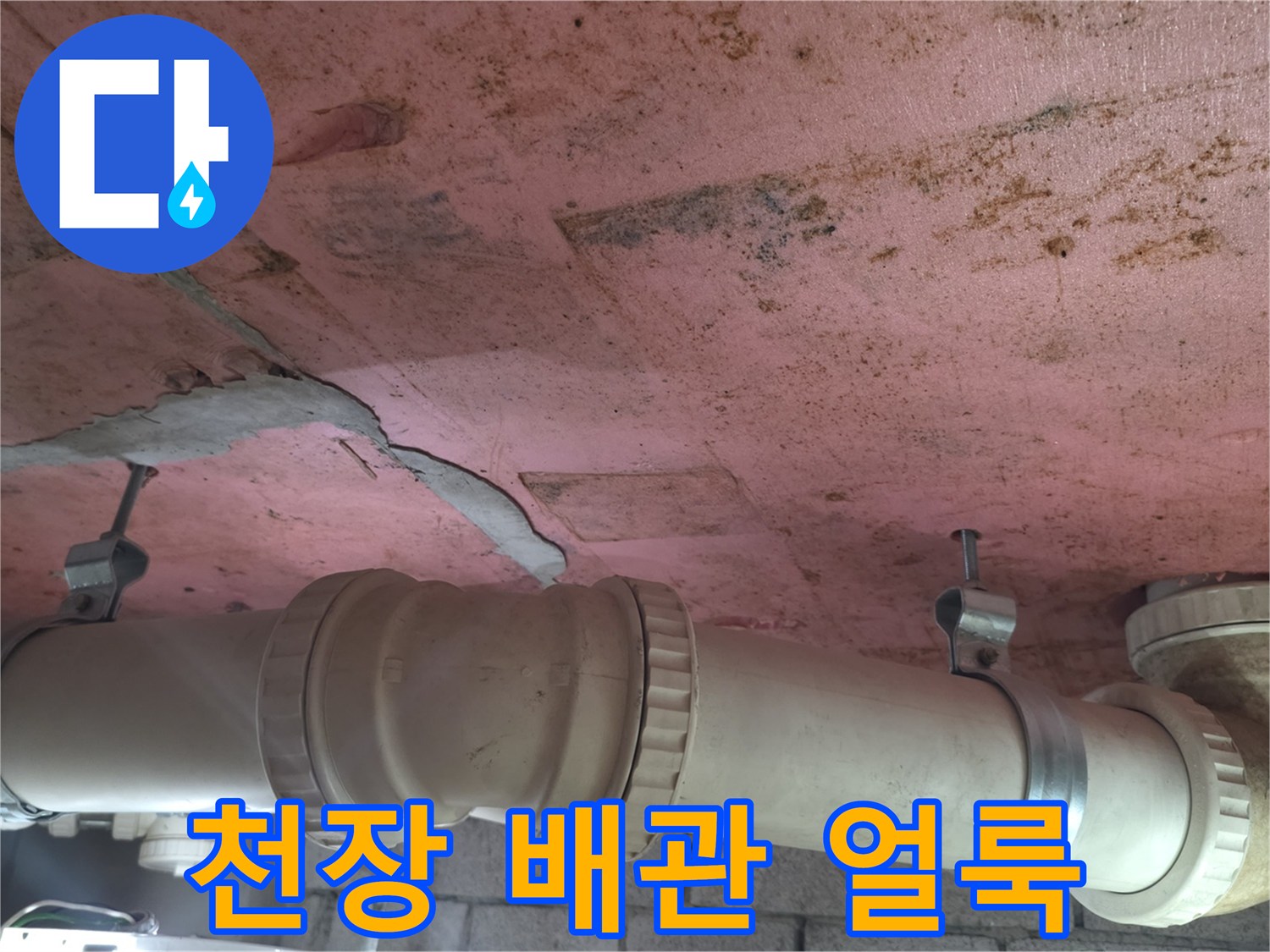 분홍색 천장 마감재-배관 주변의 누수 흔적과 균열 상태를 보여주는 사진입니다.