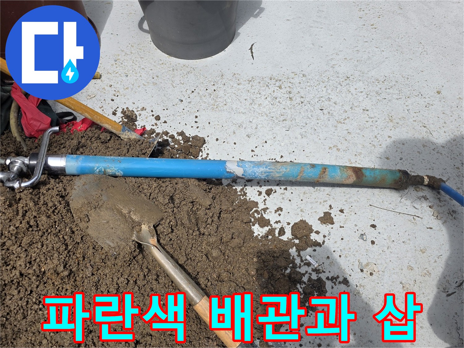 마당 굴착 부위에 드러난 파란색 PE 배관과 작업 도구
