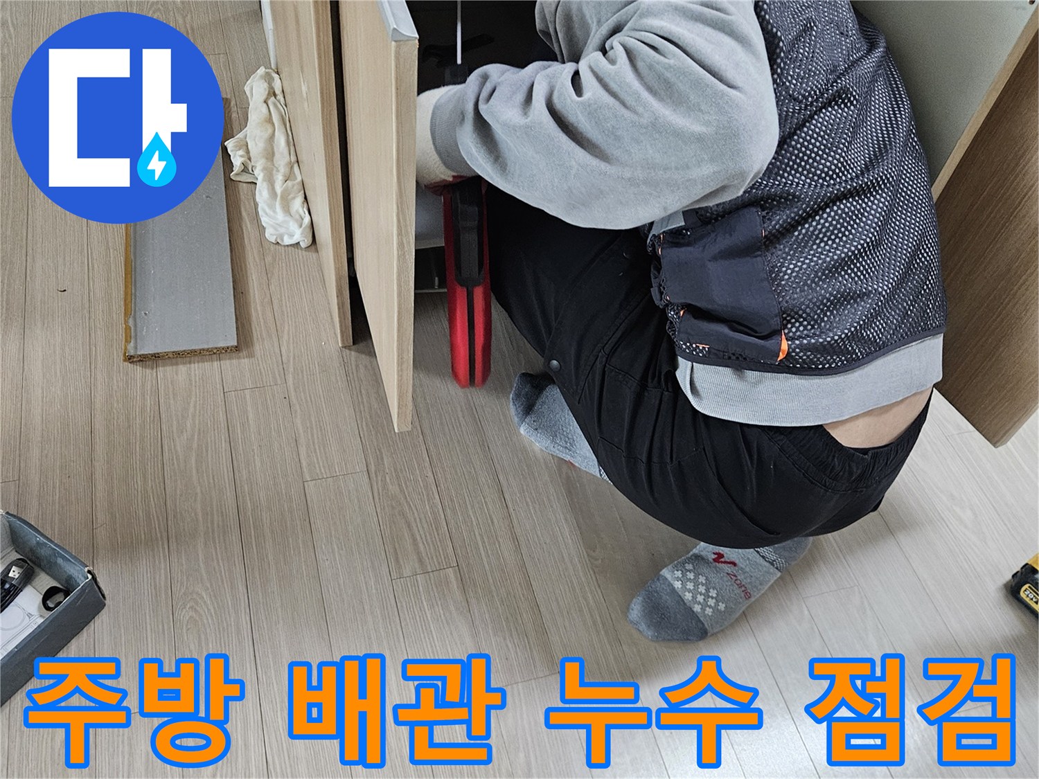 싱크대 하단 배관의 파손 부위를 찾기 위해 집중하여 작업하는 장면입니다.