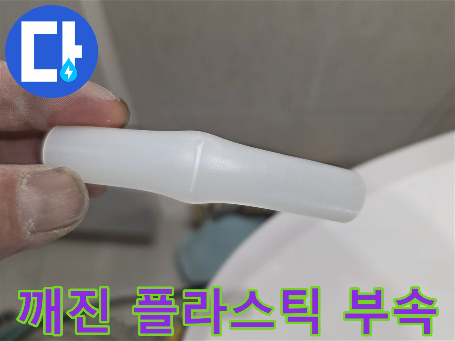 손가락으로 잡고 있는 균열된 하얀색 배관 연결 부품