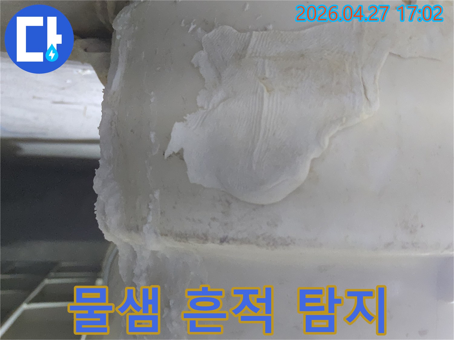 배관에서-물이 새면서-생긴-하얀-석회질 침전물과-함께-오염된-천 조각이-붙어있는-누수 현장의-사진입니다.