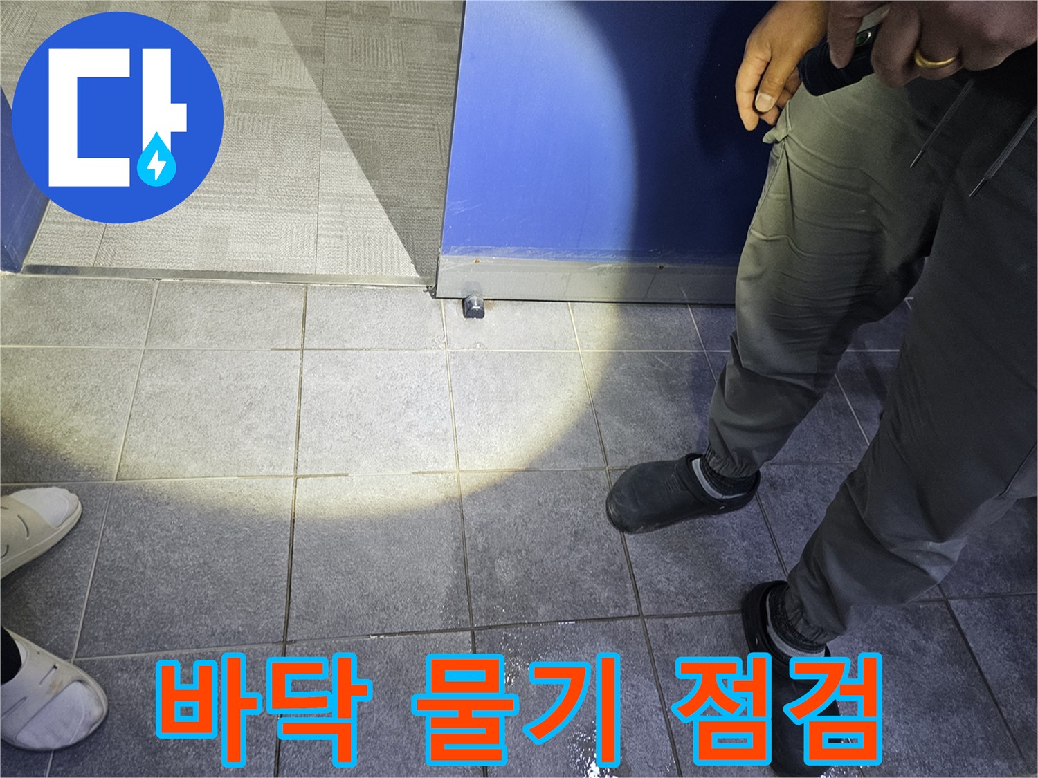 누수 탐지 전문가가 바닥에 고인 물기를 보고-누수 발생 여부와 대략적인 위치를 파악하고 있습니다.