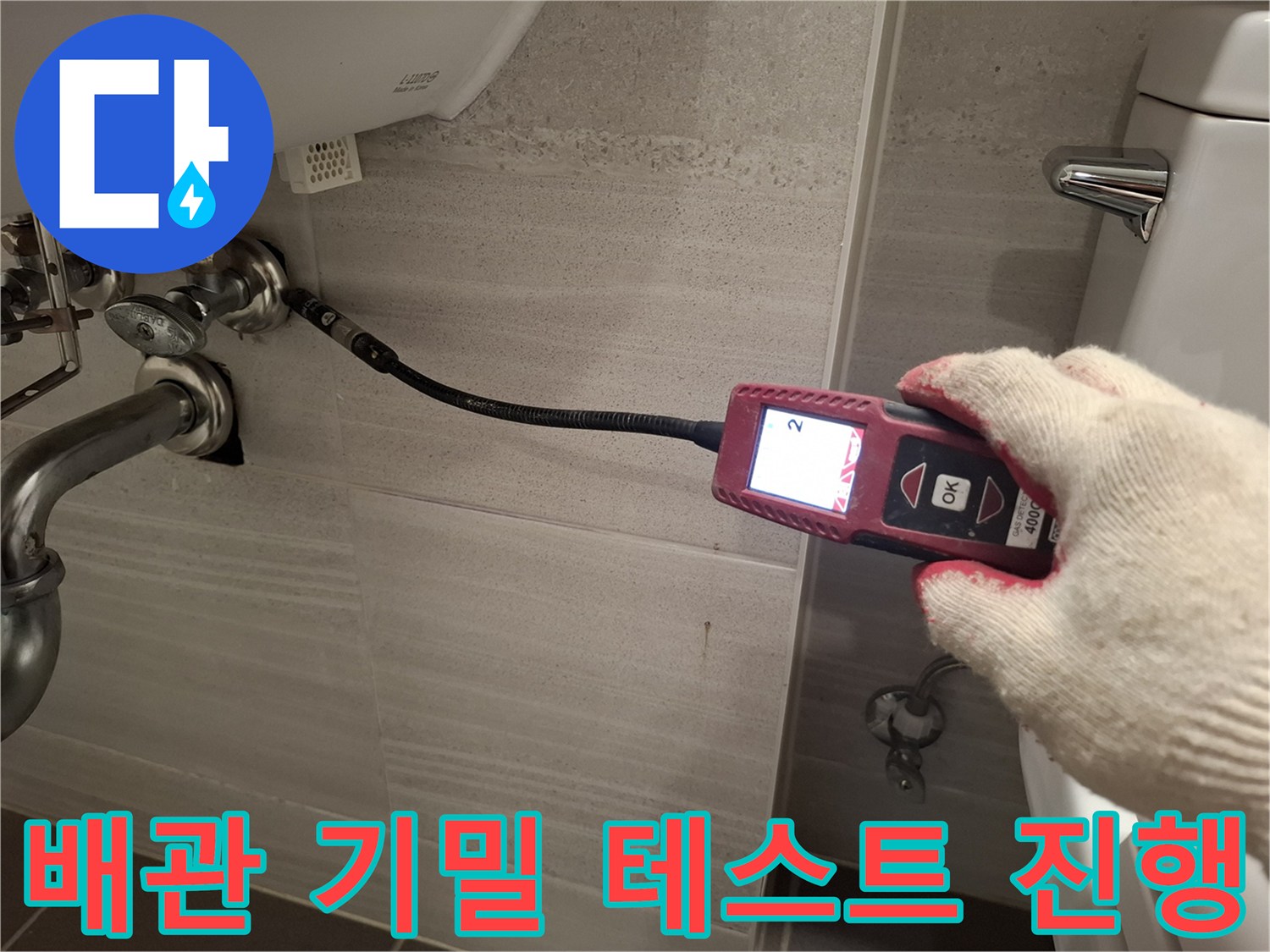 배관의 기밀 상태를 확인하기 위해 압력계를 세면대 부속에 연결한 사진입니다.