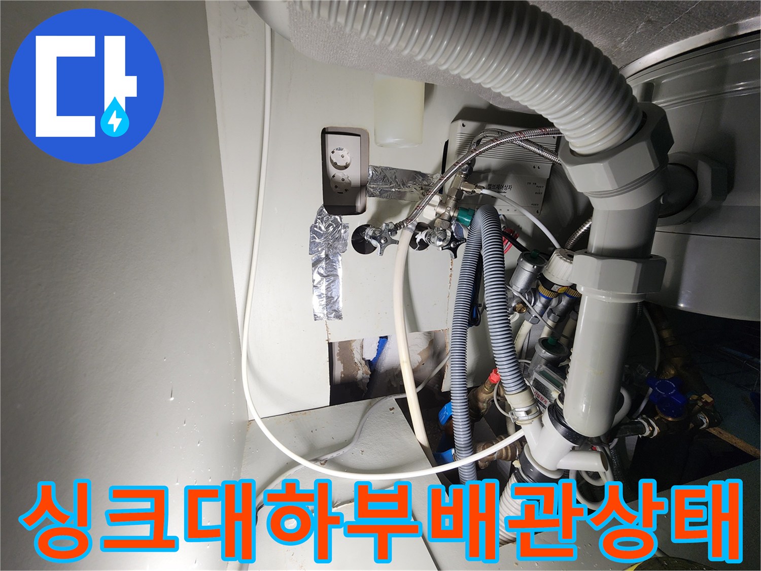싱크대 아래쪽의 은색 테이프가 감긴 배관과 굵은 호스 연결 부위