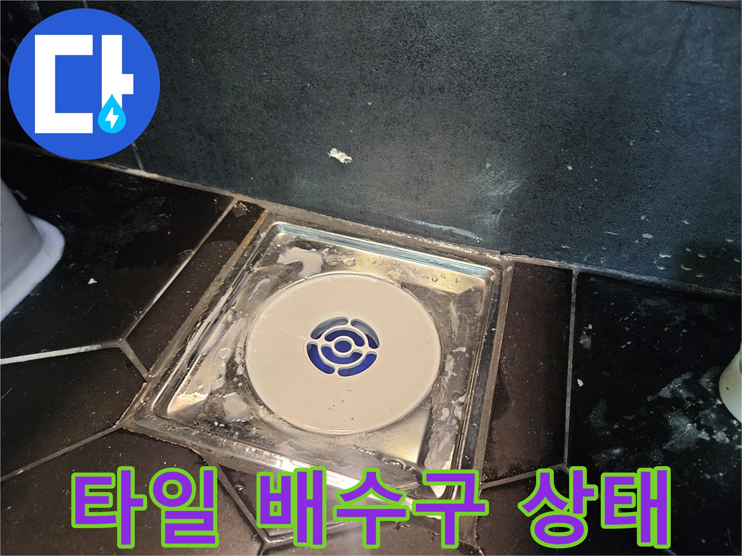 검정 타일과 흰색 배수 트랩의 경계 부위