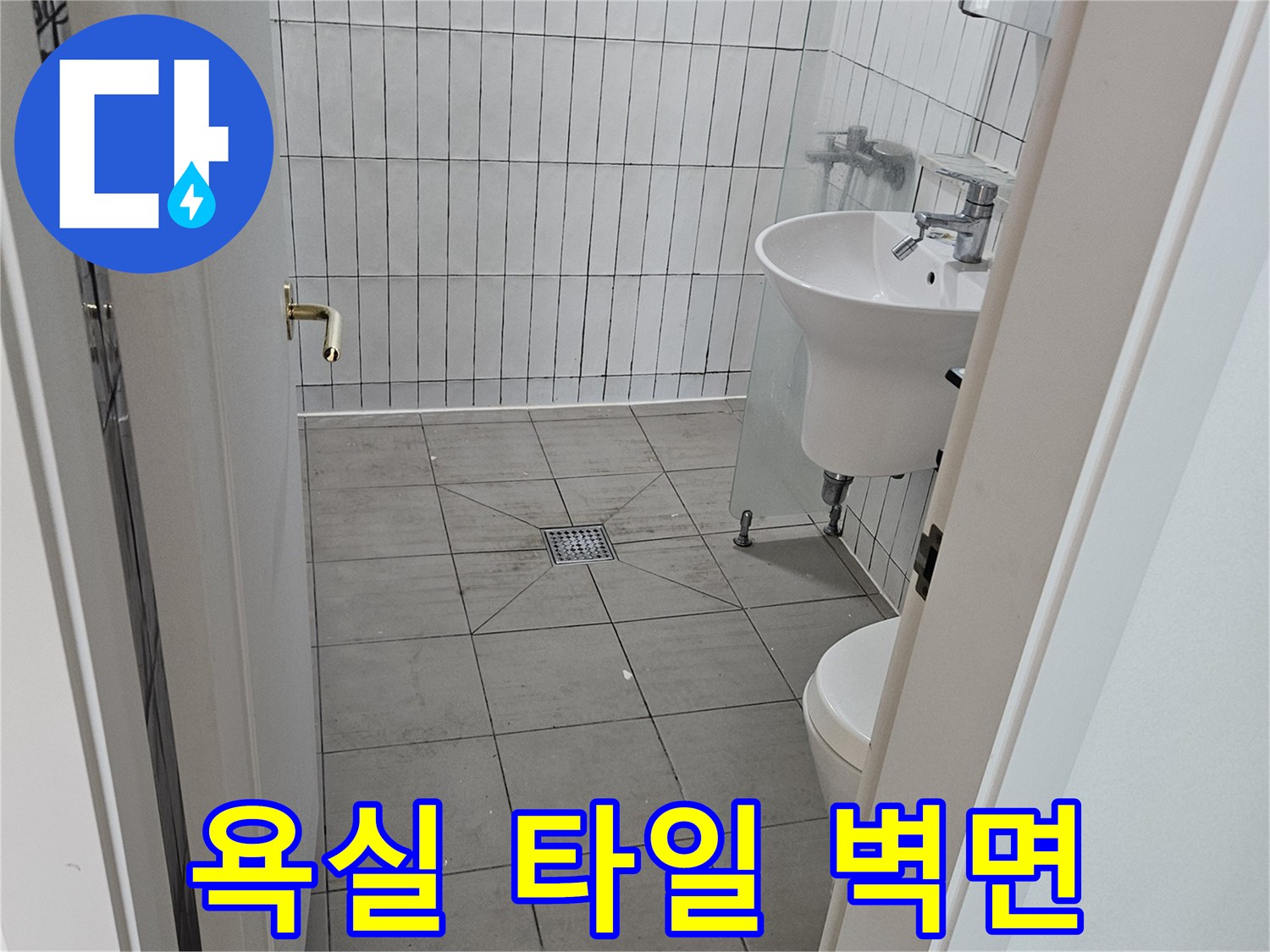 화장실 내부의 흰색 타일과 세면대 배관 구조 사진