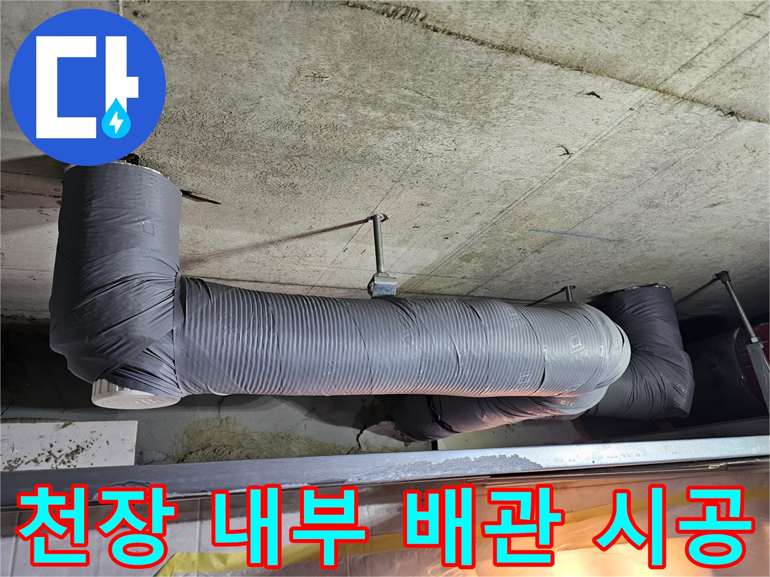 콘크리트 천장에 고정된 은색 테이핑 처리된 하수관