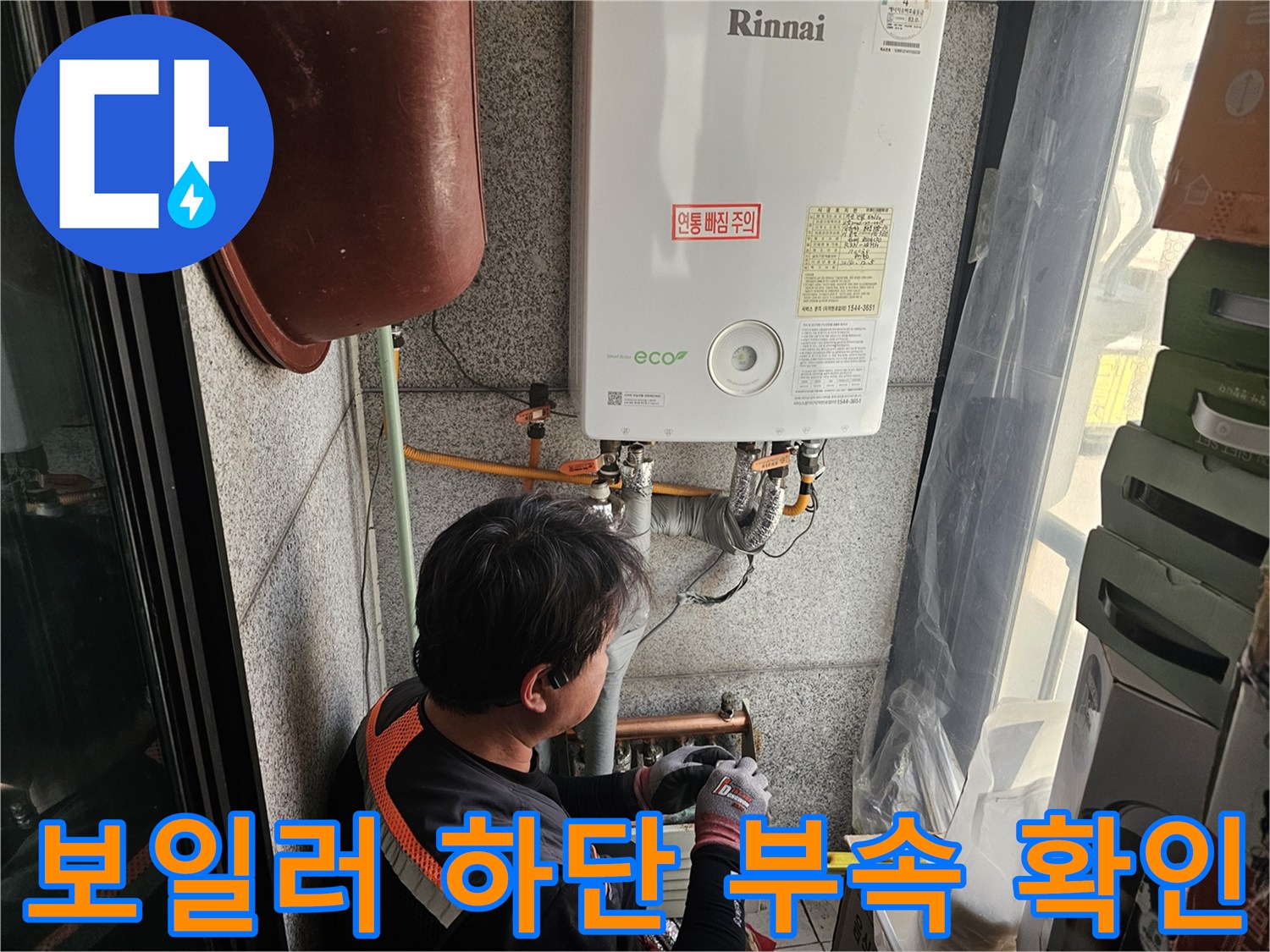 보일러 아래쪽 금속 부속과 배관을 점검하는 모습