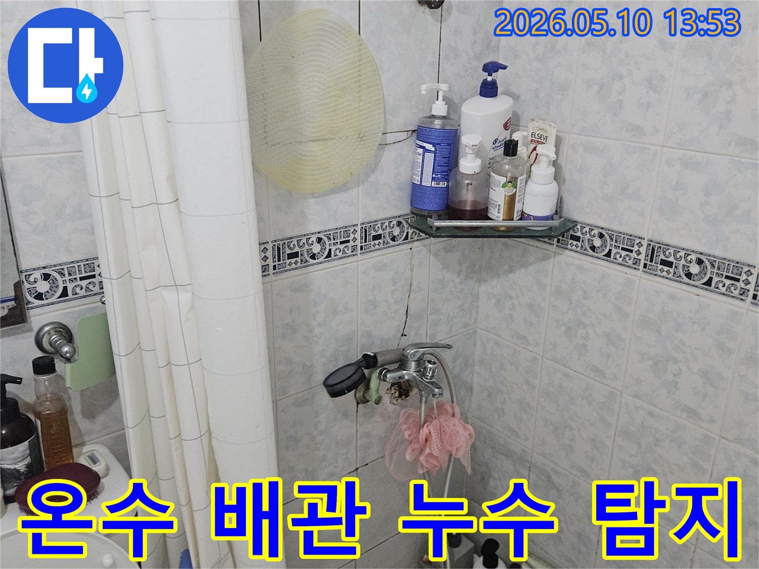욕실 샤워 공간에서 온수 배관의 잠재적 누수 지점을 파악하기 위해 주변을 살피는 모습
