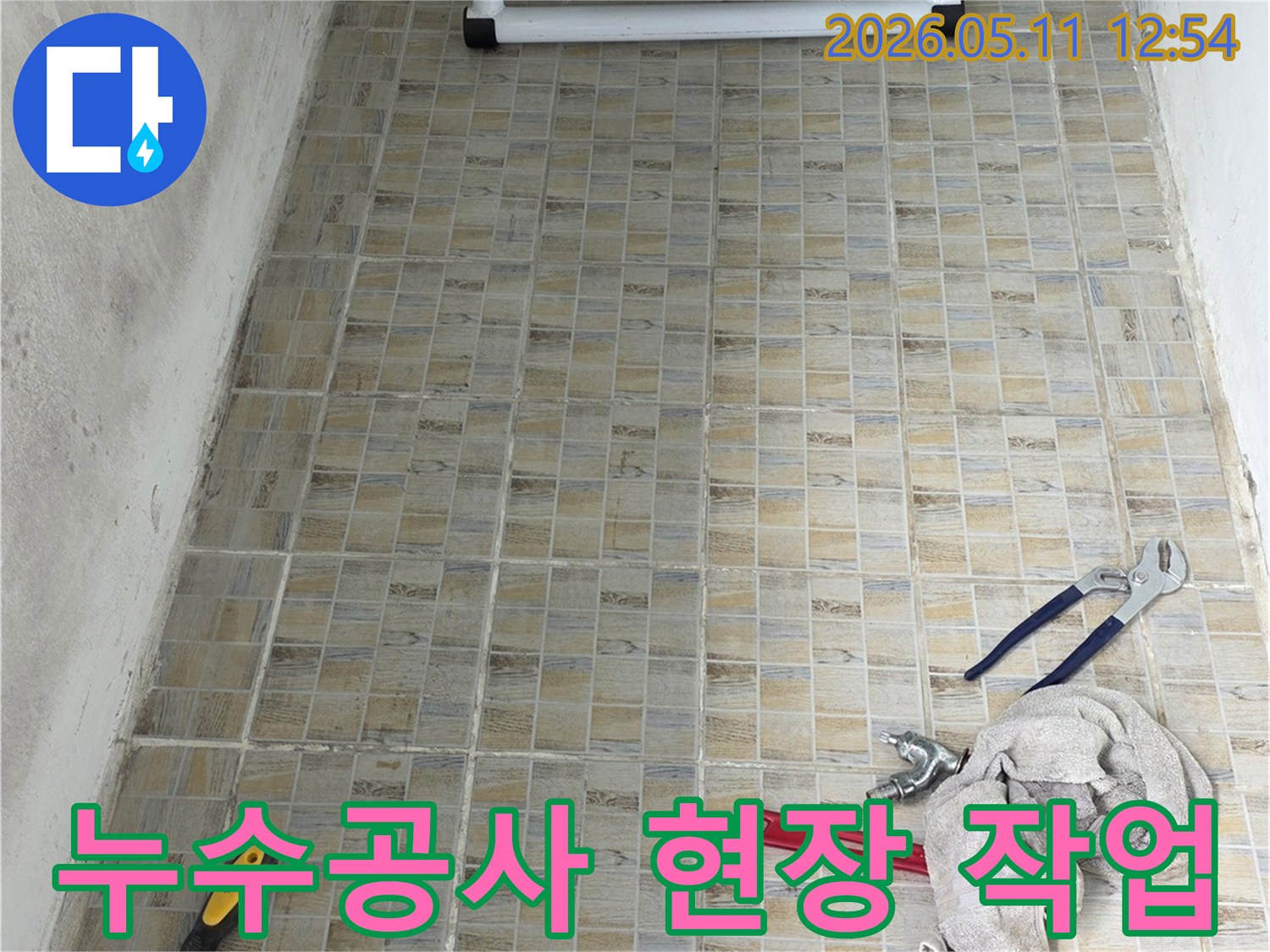 누수 공사 현장에서-타일 벽면과-작업에 필요한 공구들이 준비된 모습