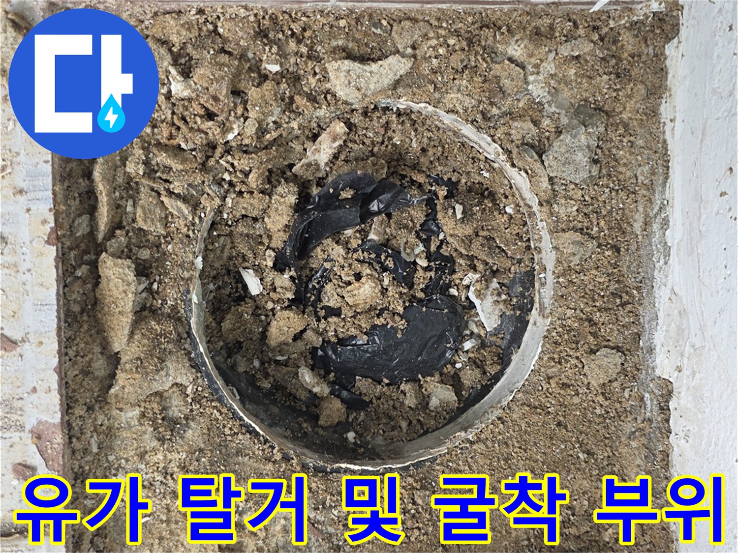 배수관 주변의 젖은 흙과 깨진 방수층을 보여주는 사진입니다.