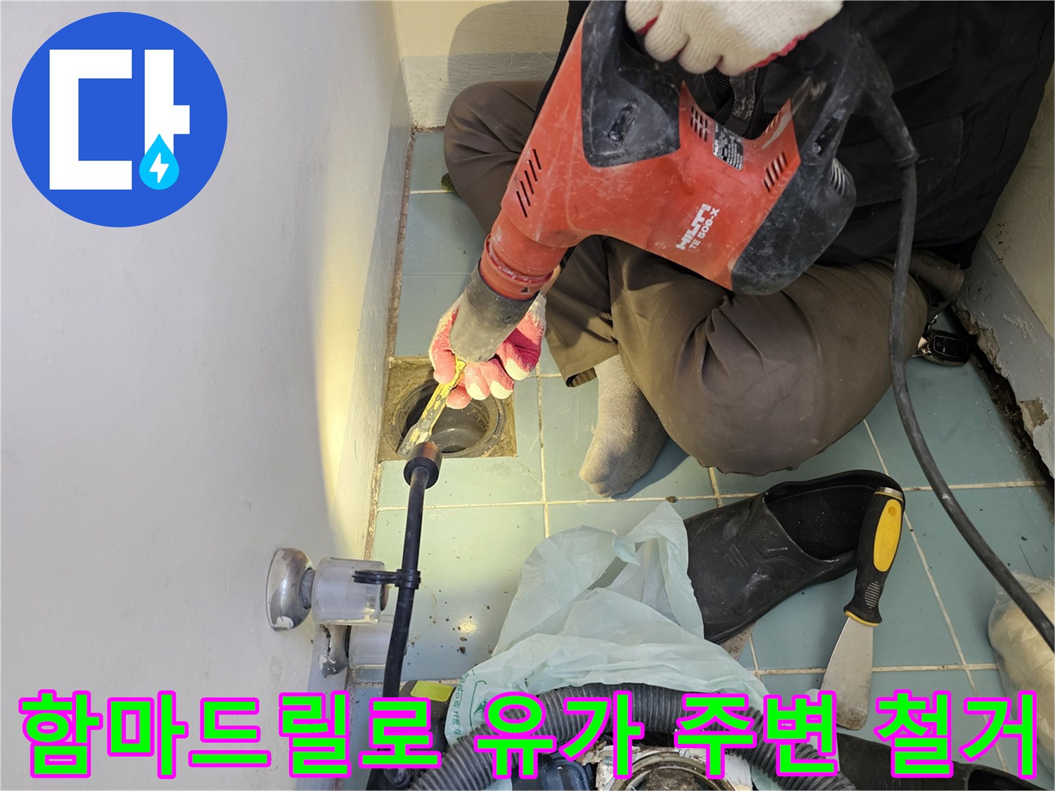 함마드릴을 사용하여-세탁실 배수구 주변 타일을 제거하는 모습