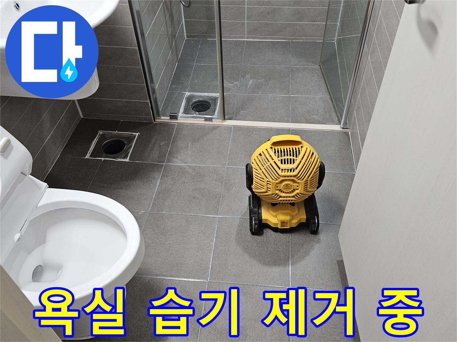 화장실 타일 벽면에 설치된 산업용 송풍기와 변기 주변의 작업 환경