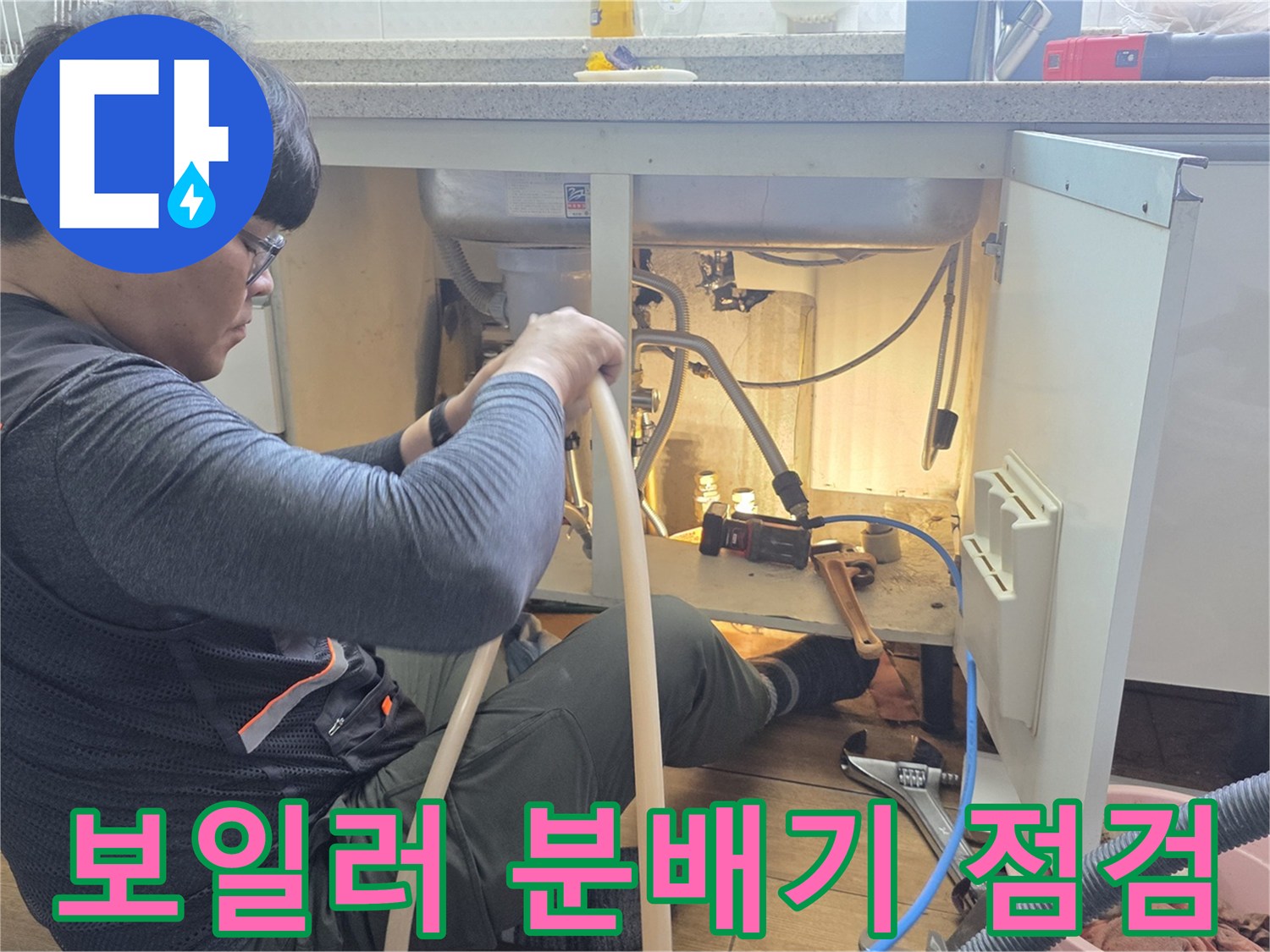 하부장 내부의 복잡한 보일러 분배기 배관을 정밀하게 진단하는 작업자