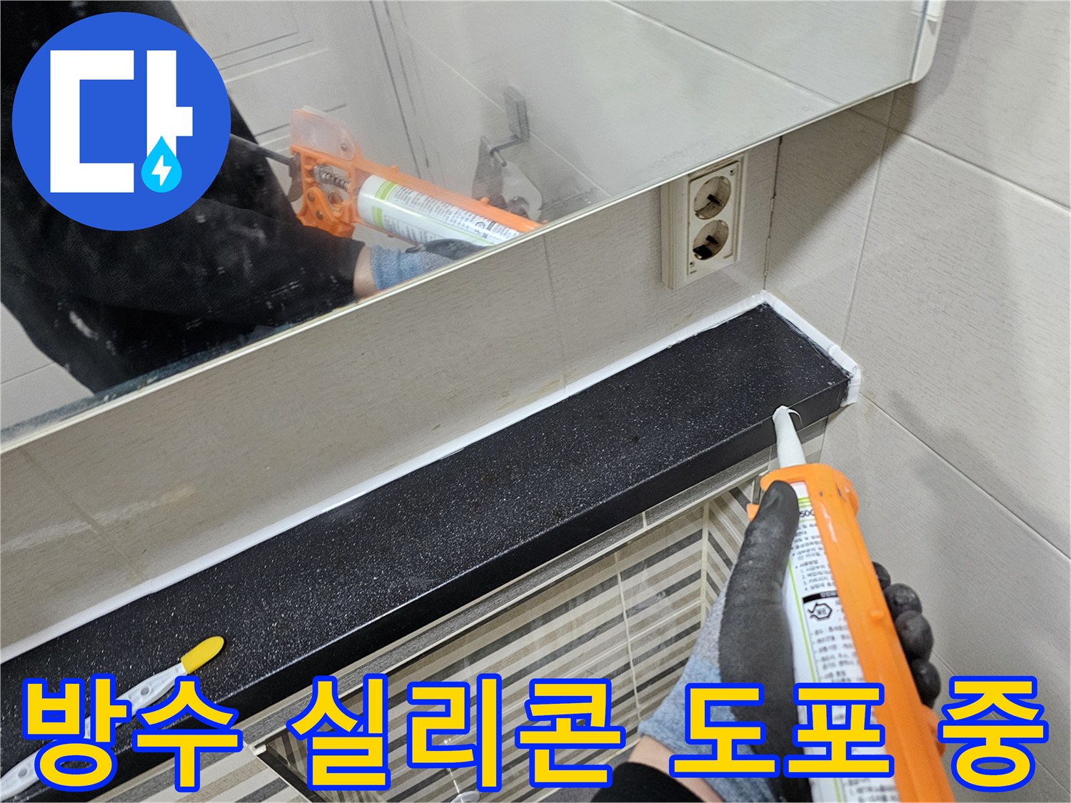 검은색 선반 하단에 하얀 실리콘을 쏘아 올리는 작업자 손