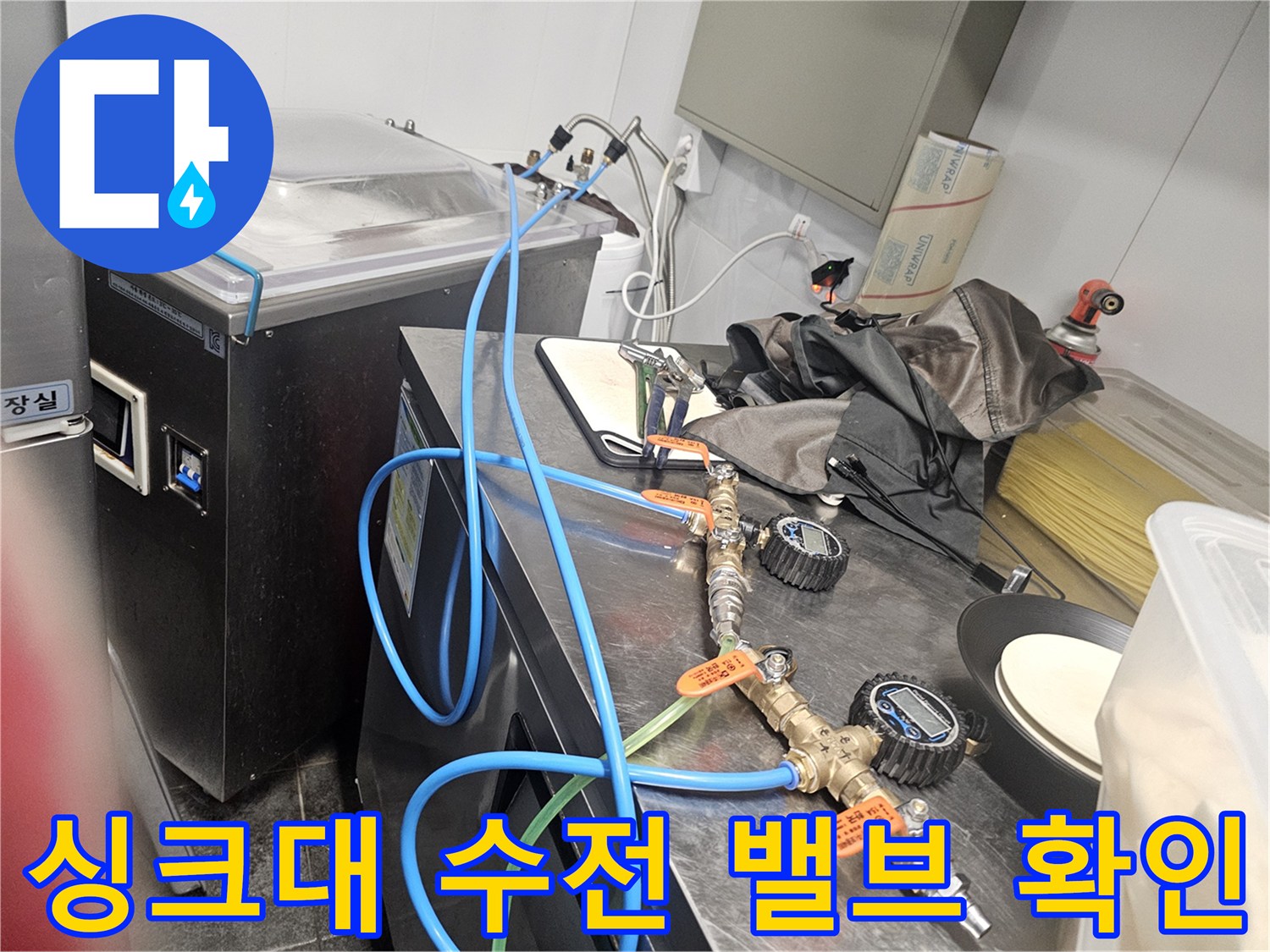 주방 싱크대 아래쪽의 파란색 호스와 금속 재질의 밸브 연결 상태 사진