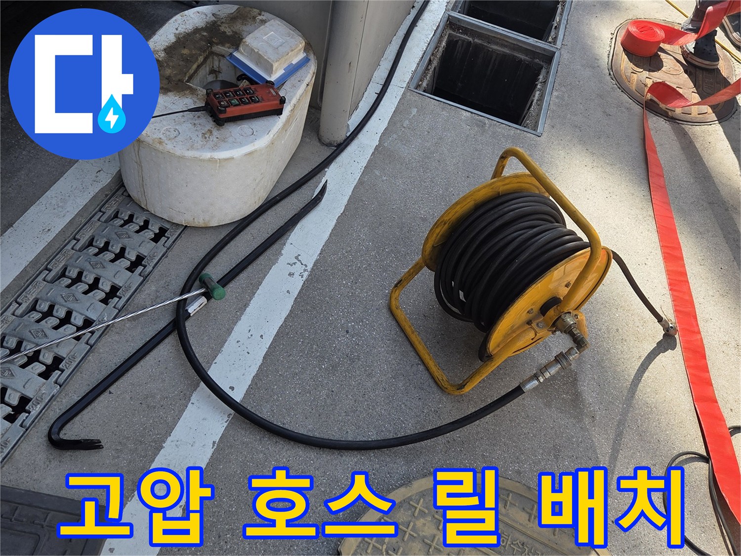 맨홀 근처에 놓인 - 작업용 고압 세척 호스 릴입니다.