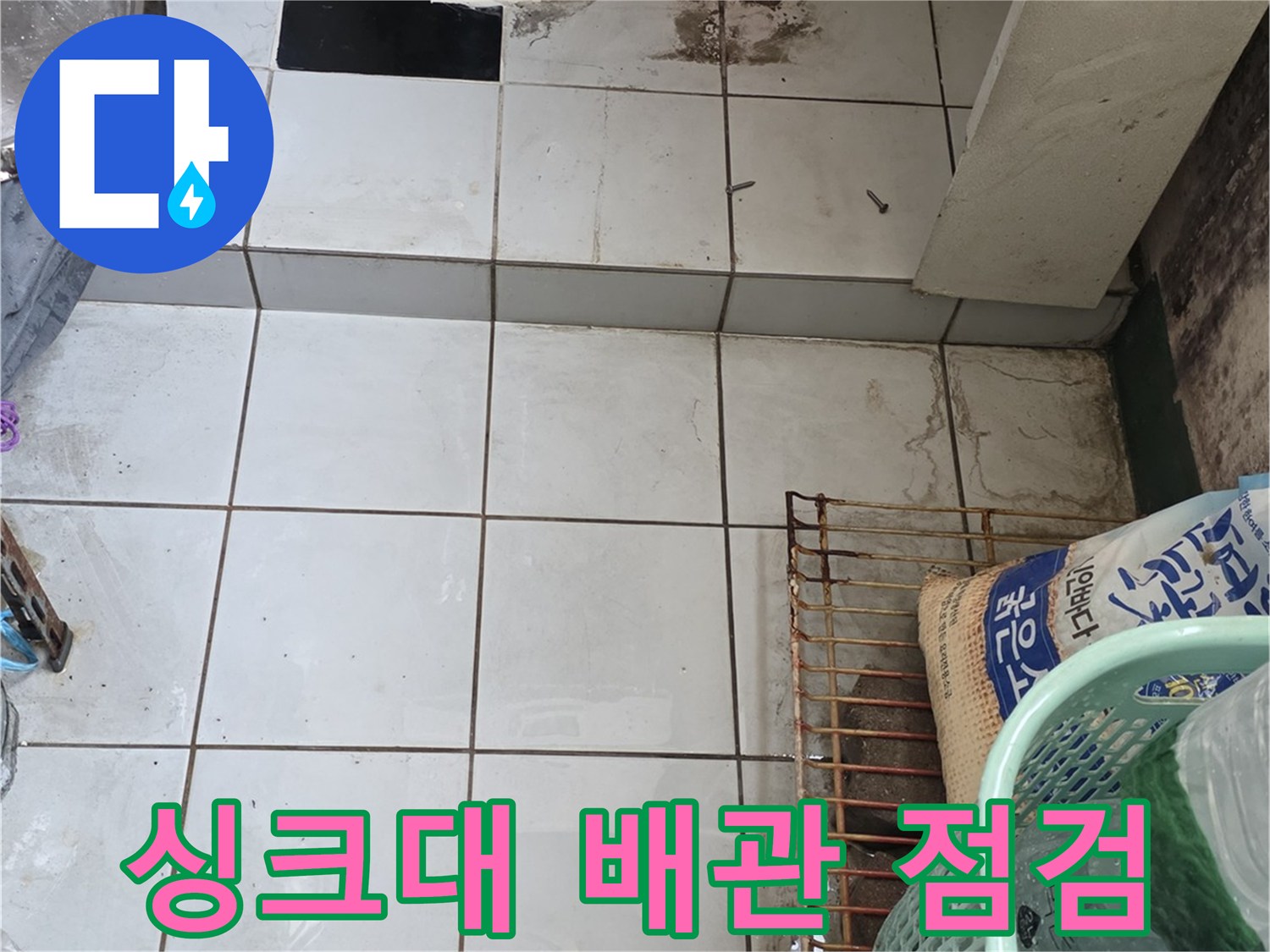 싱크대 하부의 파란색 배관과 주변 타일 벽면 사진