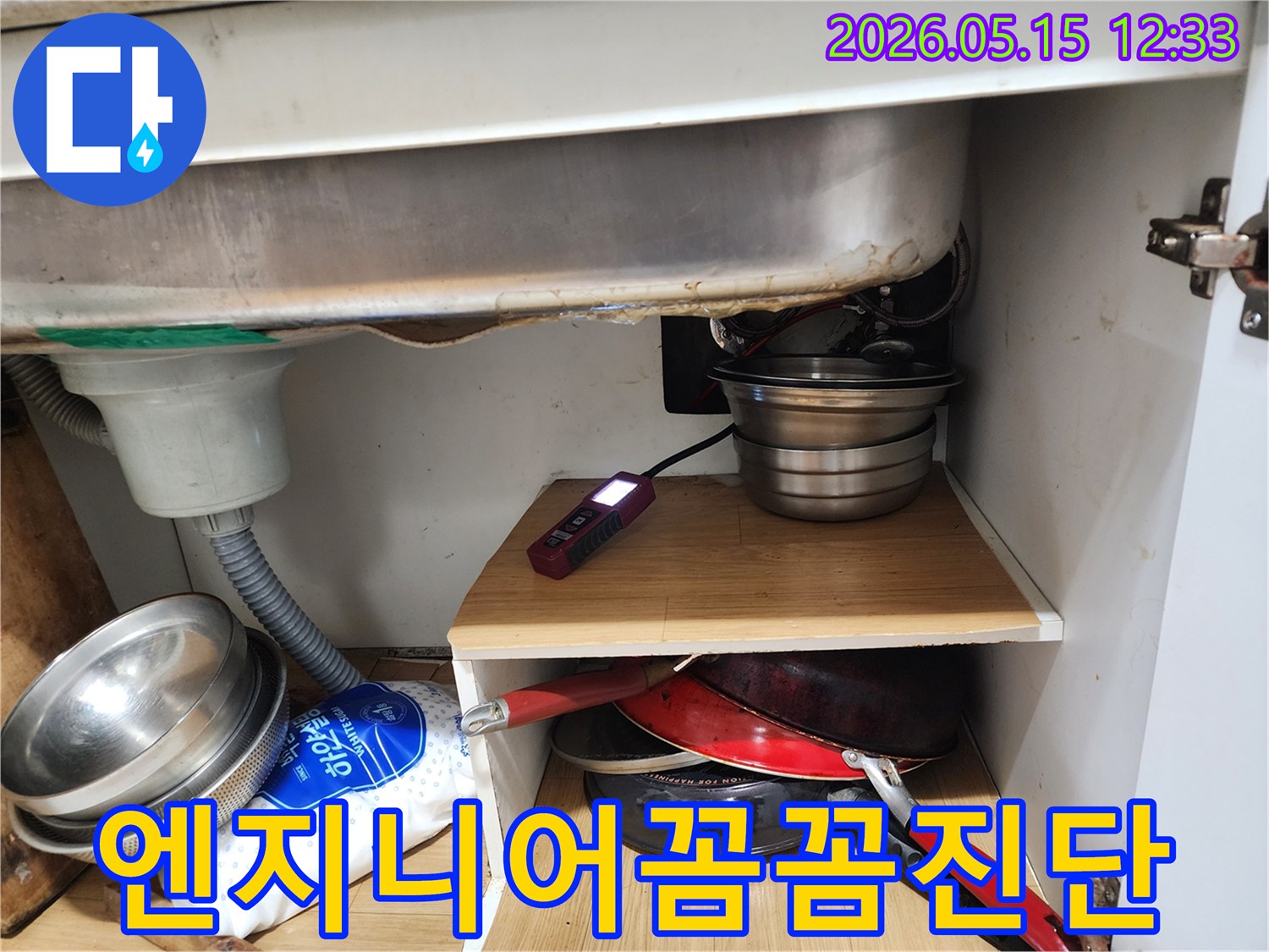 A professional engineer is meticulously inspecting for leaks under a kitchen sink using a specialized detection tool.