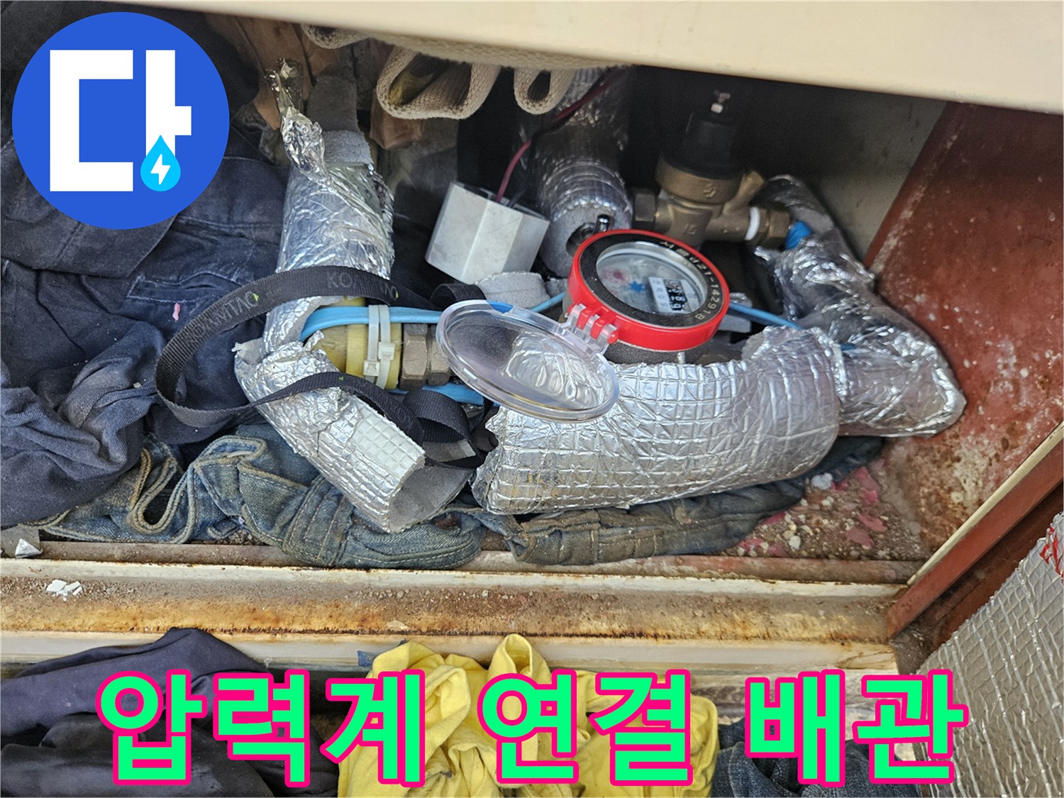 은색 보온재로 감싸진 배관에 설치된 압력 게이지
