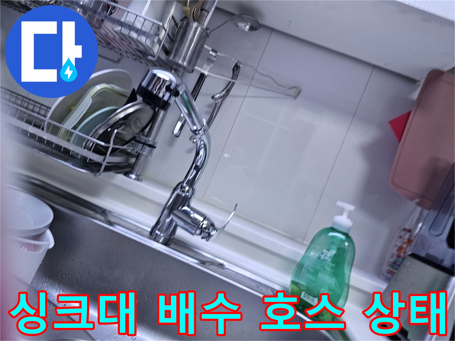 싱크대 하단 수전 및 배수 호스의 연결 상태를 보여주는 사진