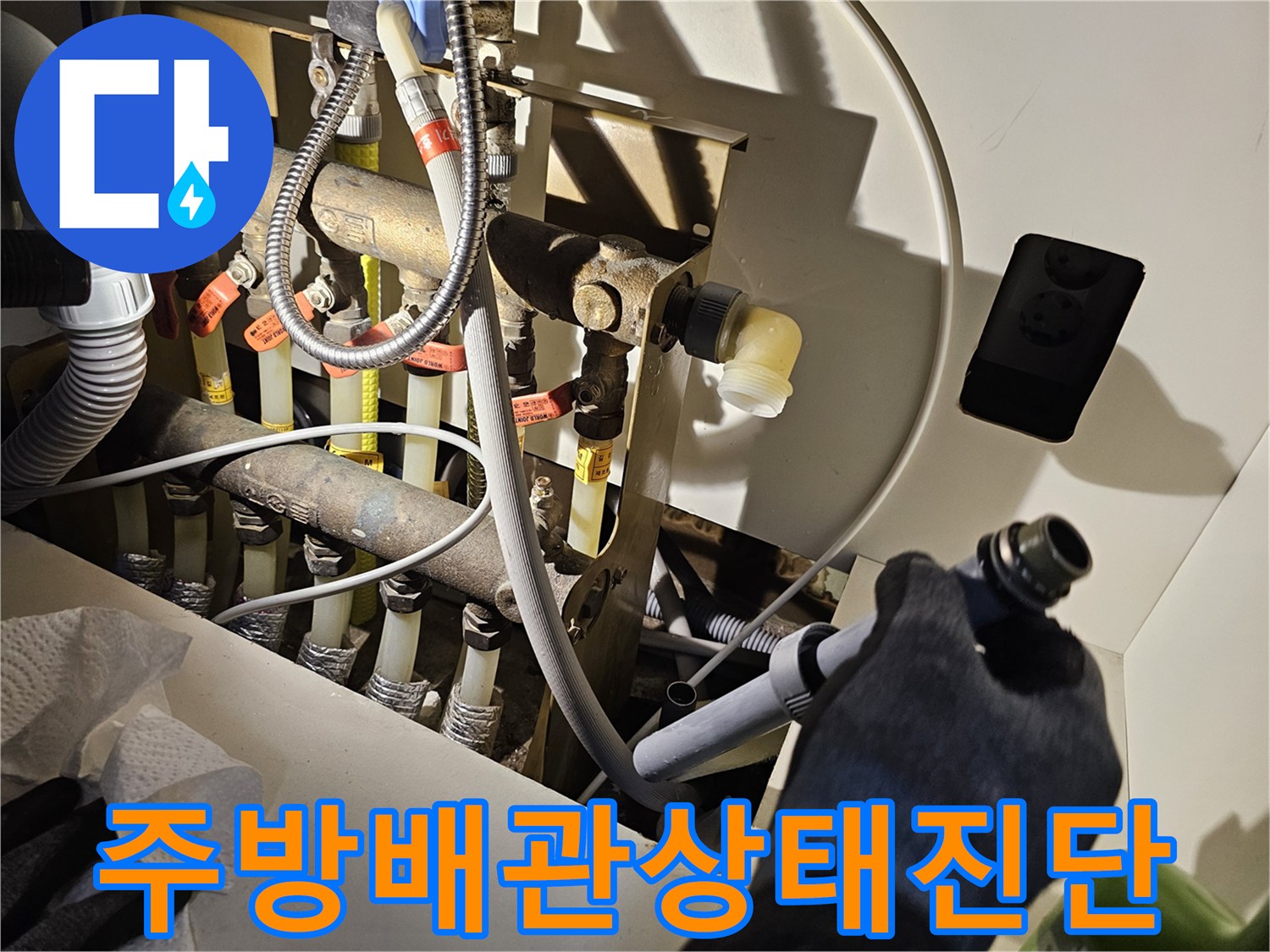 싱크대 하부의 복잡한 급배수 관로를 세밀하게 조사하는 장면