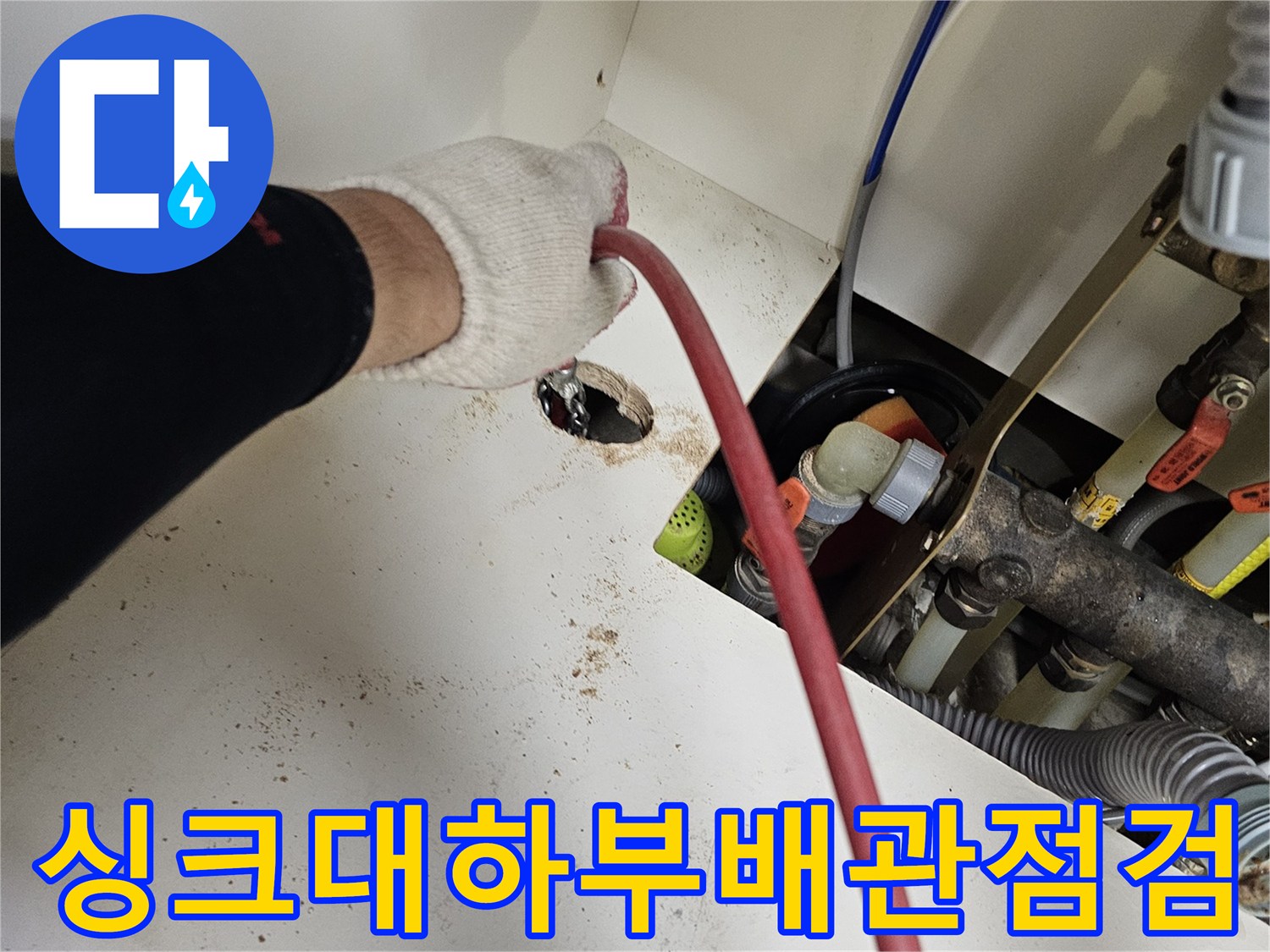싱크대 하부장 내부의 배수 배관 연결 부위를 점검하는 모습